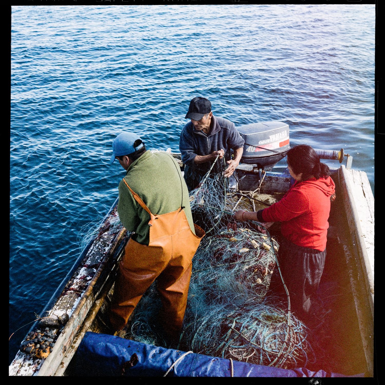 Pescadores revisando redes en un bote, en el mar de Apiao