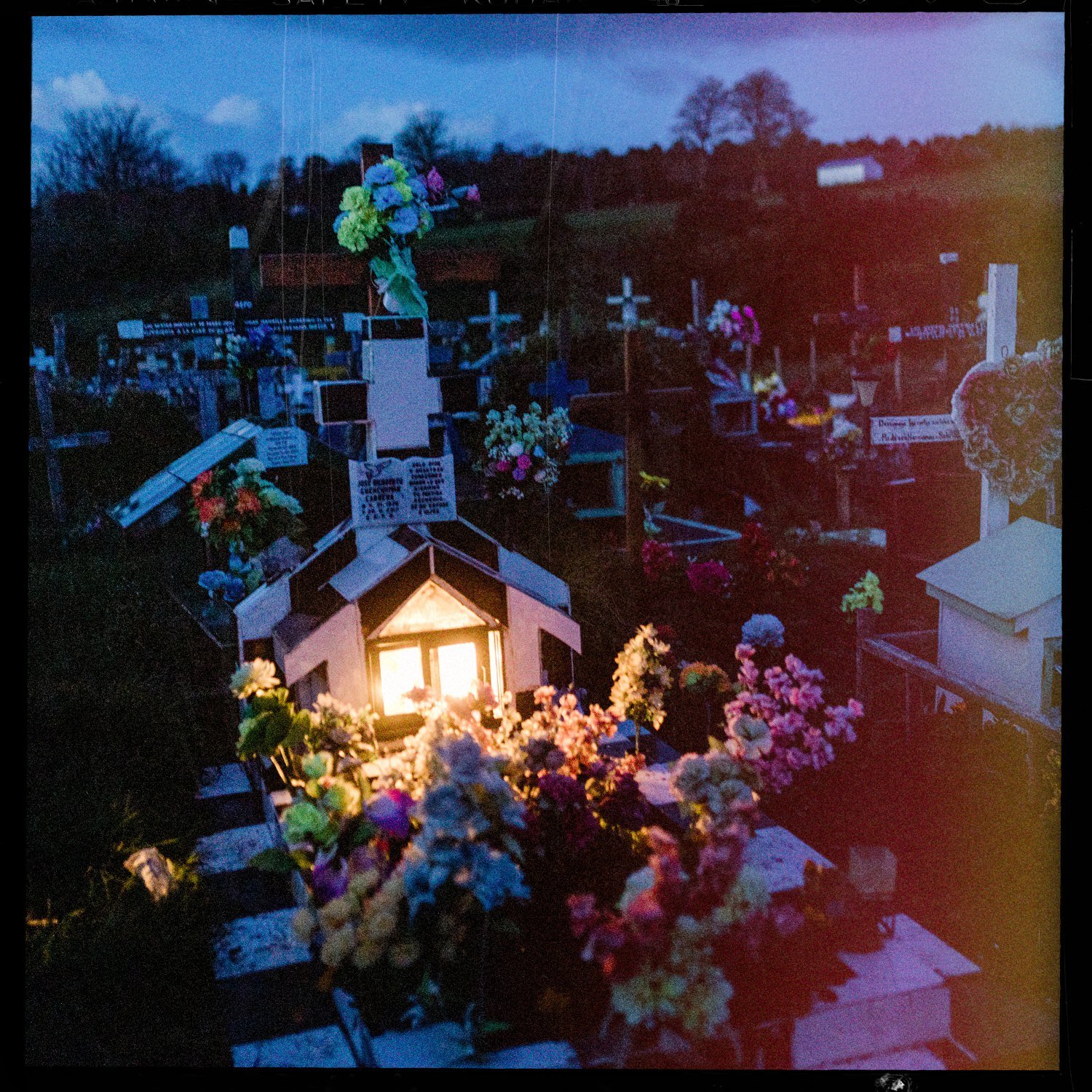 Tumba iluminada y rodeada de flores de colores en el cementerio de Apiao