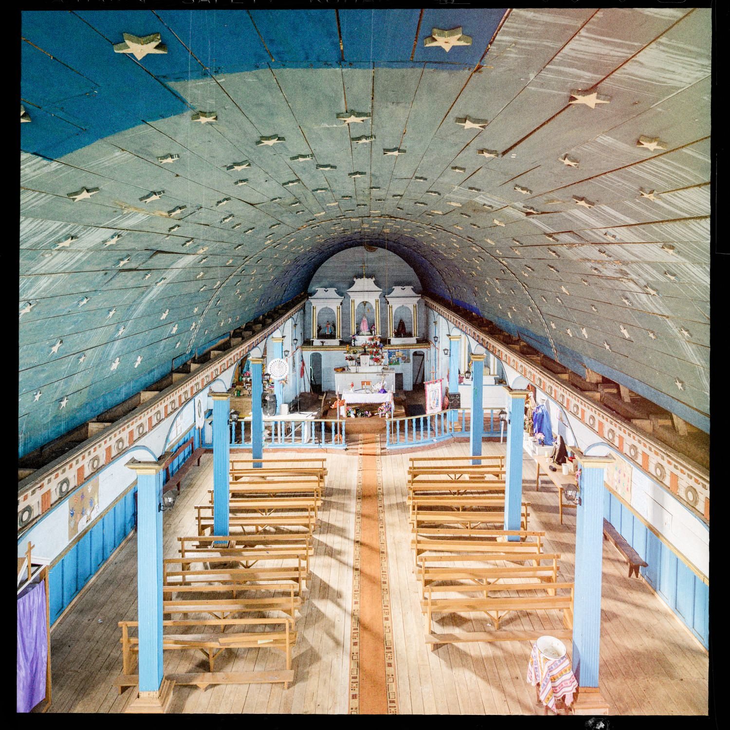 Nave de la iglesia de Apiao con bóveda azul estrellada y bancas de madera