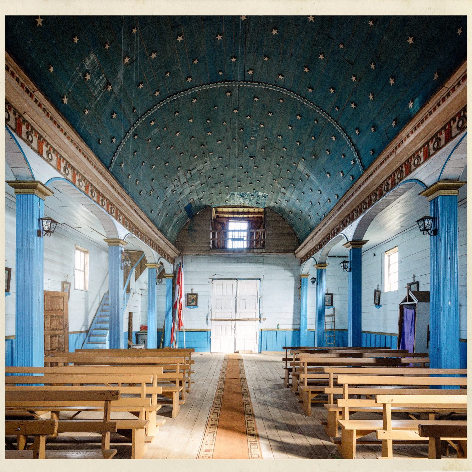 Interior de la iglesia de Apiao: nave central con columnas azules y bancas