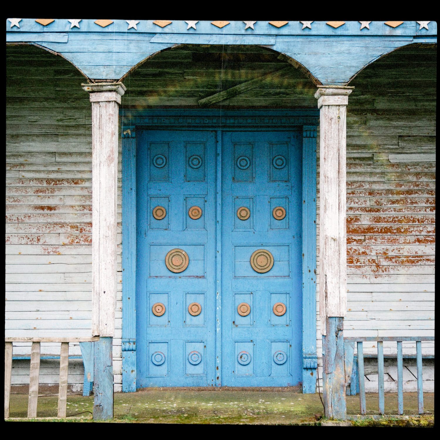 Puerta azul del pórtico de la iglesia de Apiao, entre columnas de madera