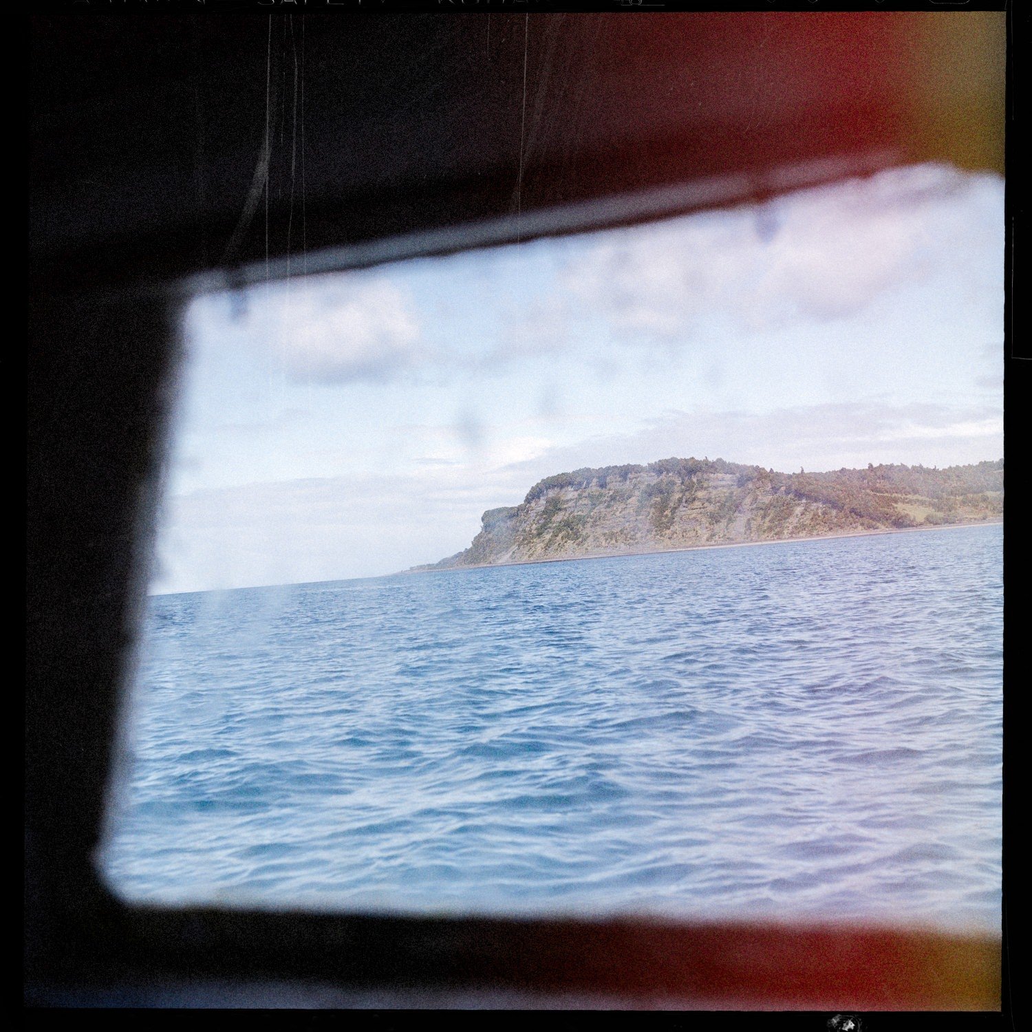 El mar y la costa vistos a través de la ventana de una embarcación
