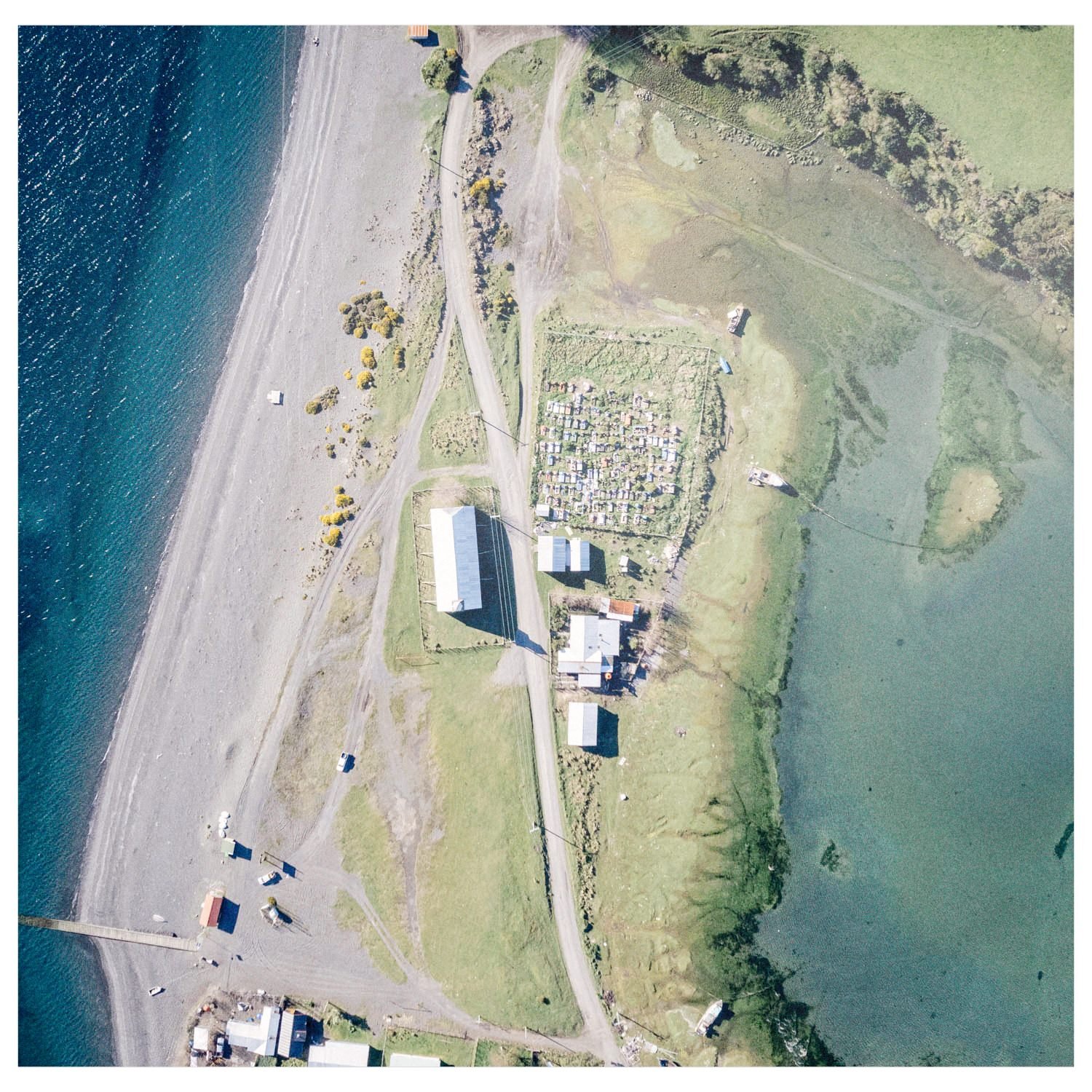 Vista aérea de la playa de Apiao, con casas y un cementerio junto al mar