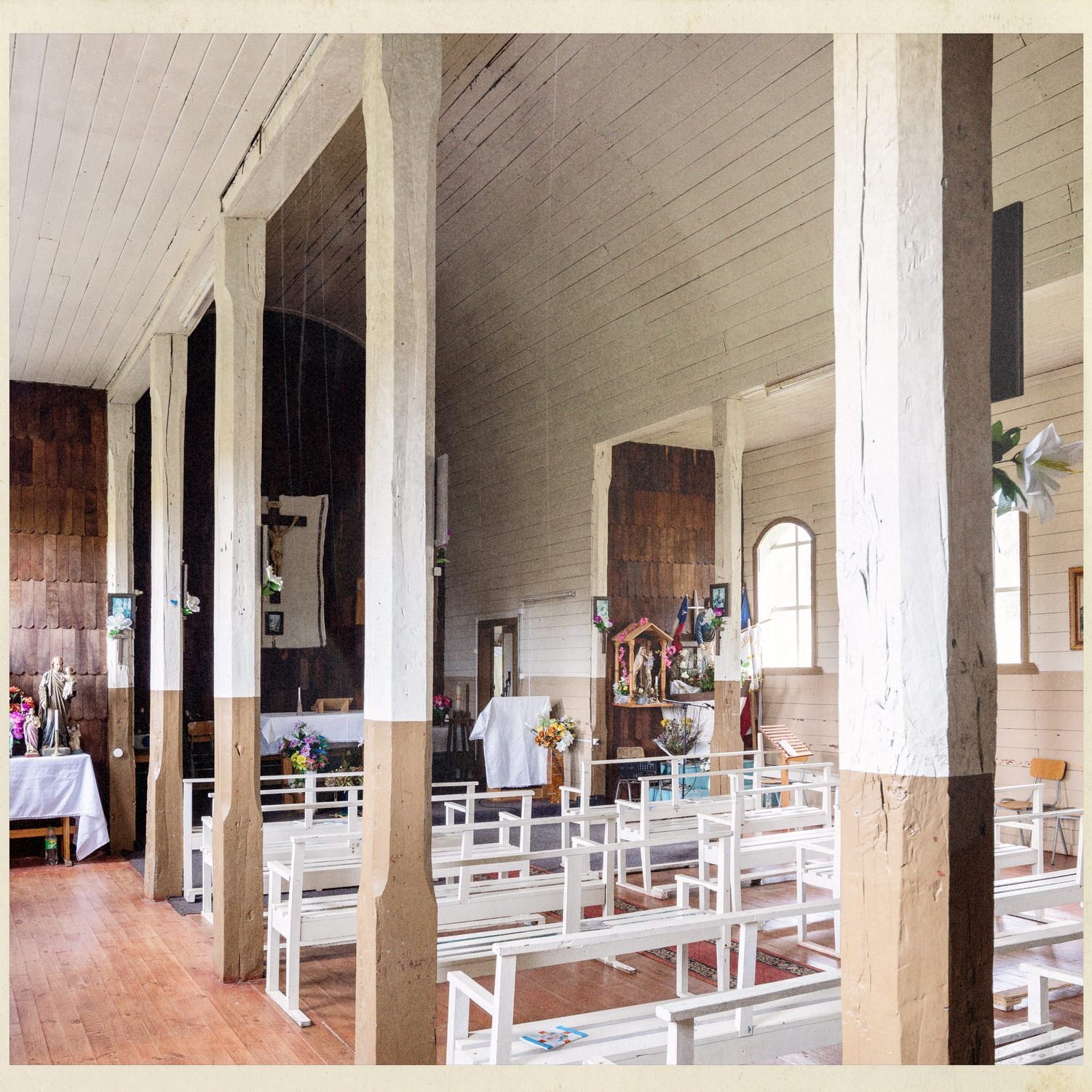 Columnas de madera y bancas en el interior de la iglesia de Caulín