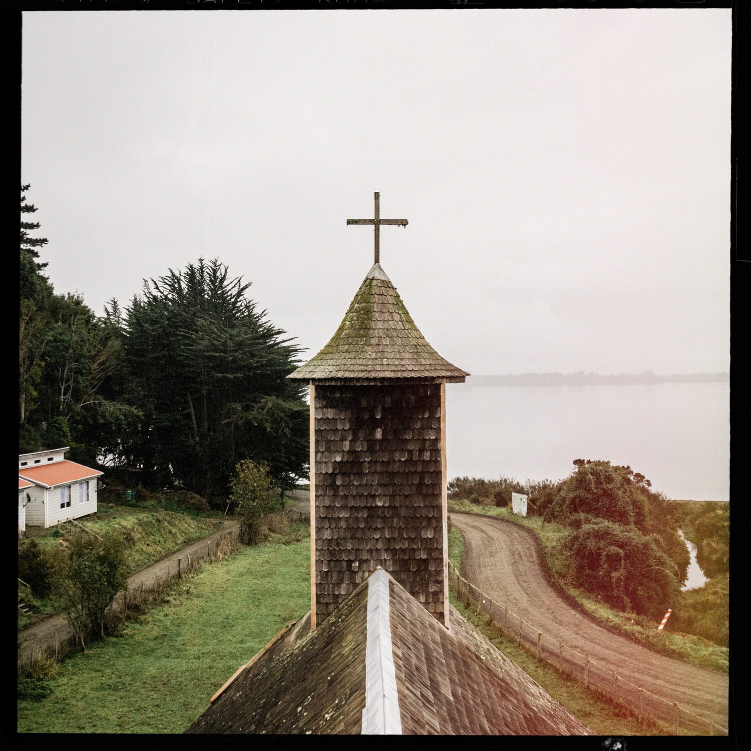 Torre de la iglesia de Caulín vista desde lo alto, con el camino y la costa