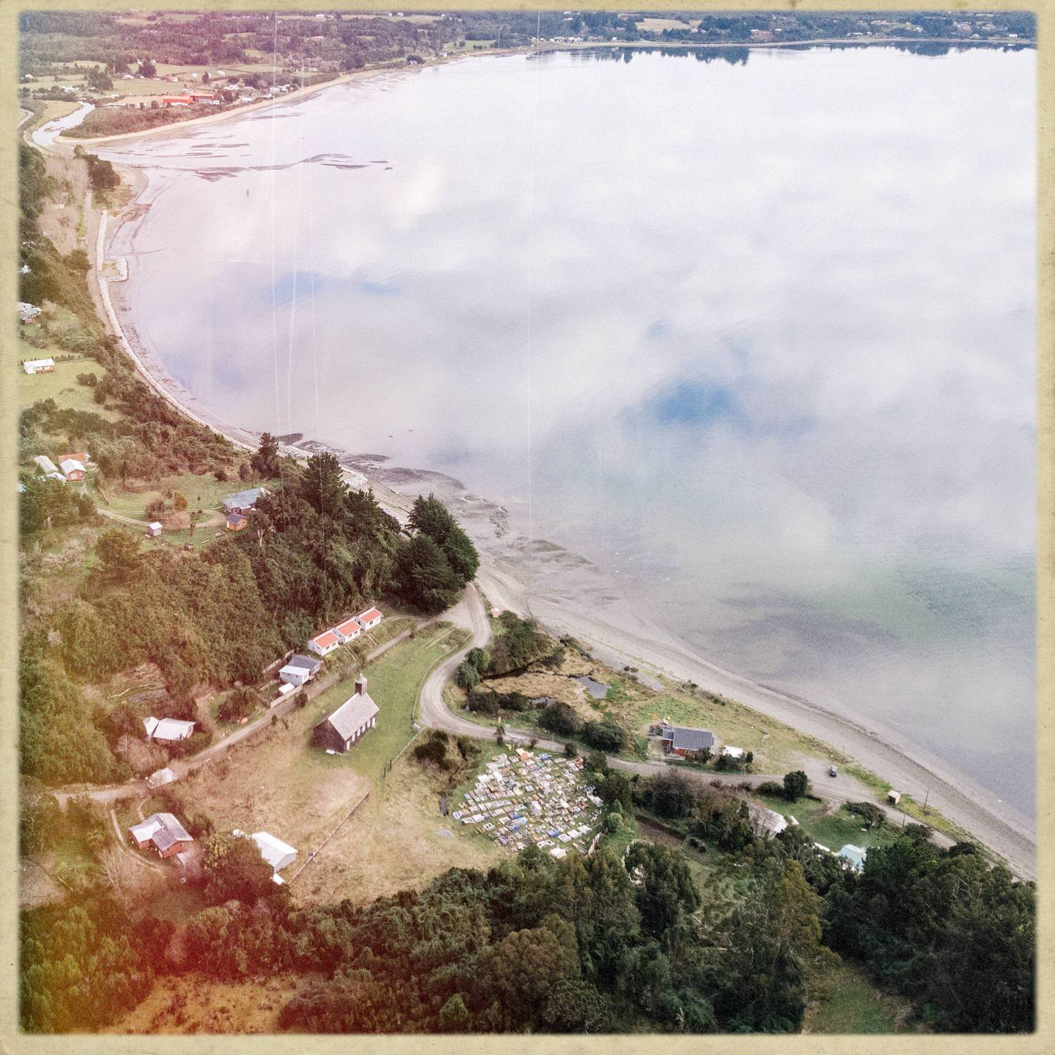 Vista aérea de la costa de Caulín, con la iglesia, el cementerio y el mar