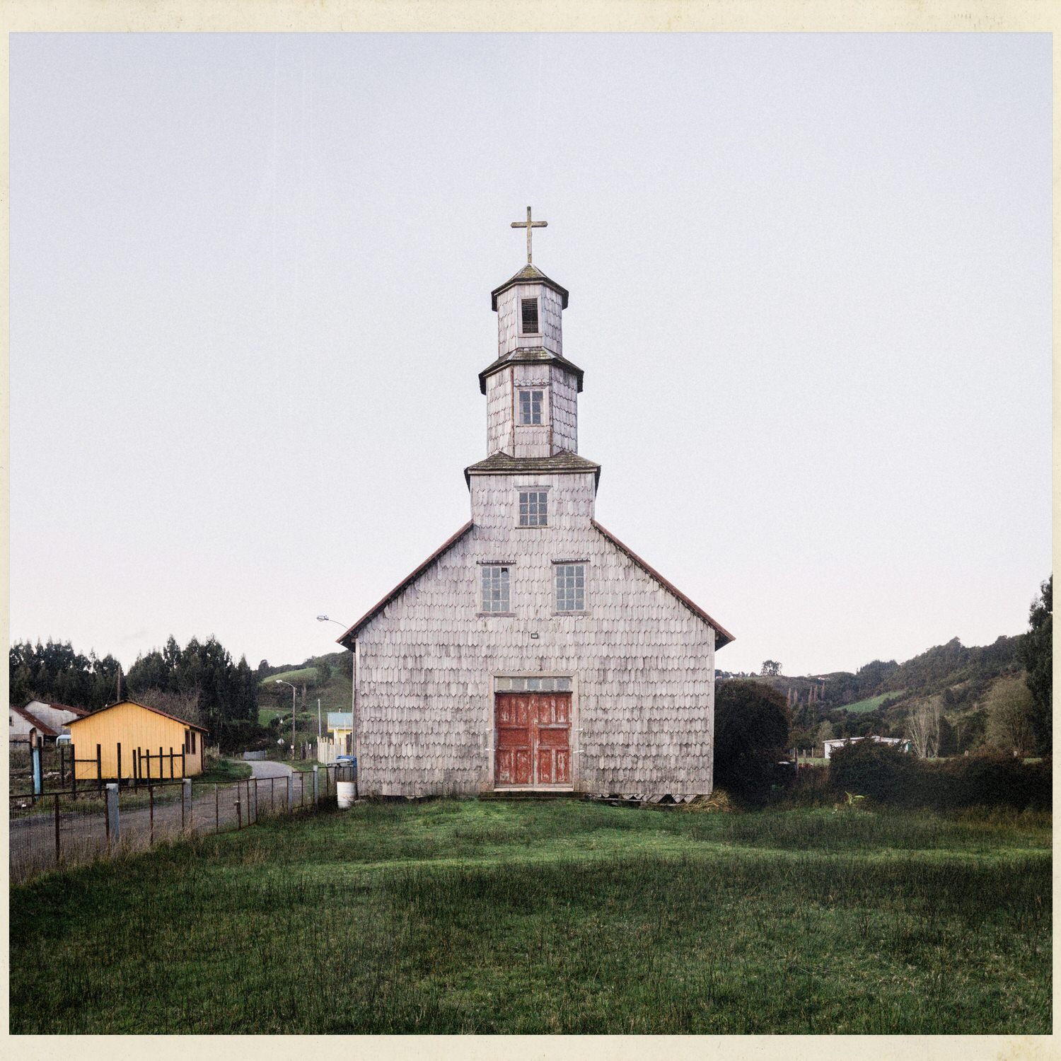 Fachada de la iglesia de Chullec con su torre y puertas rojas