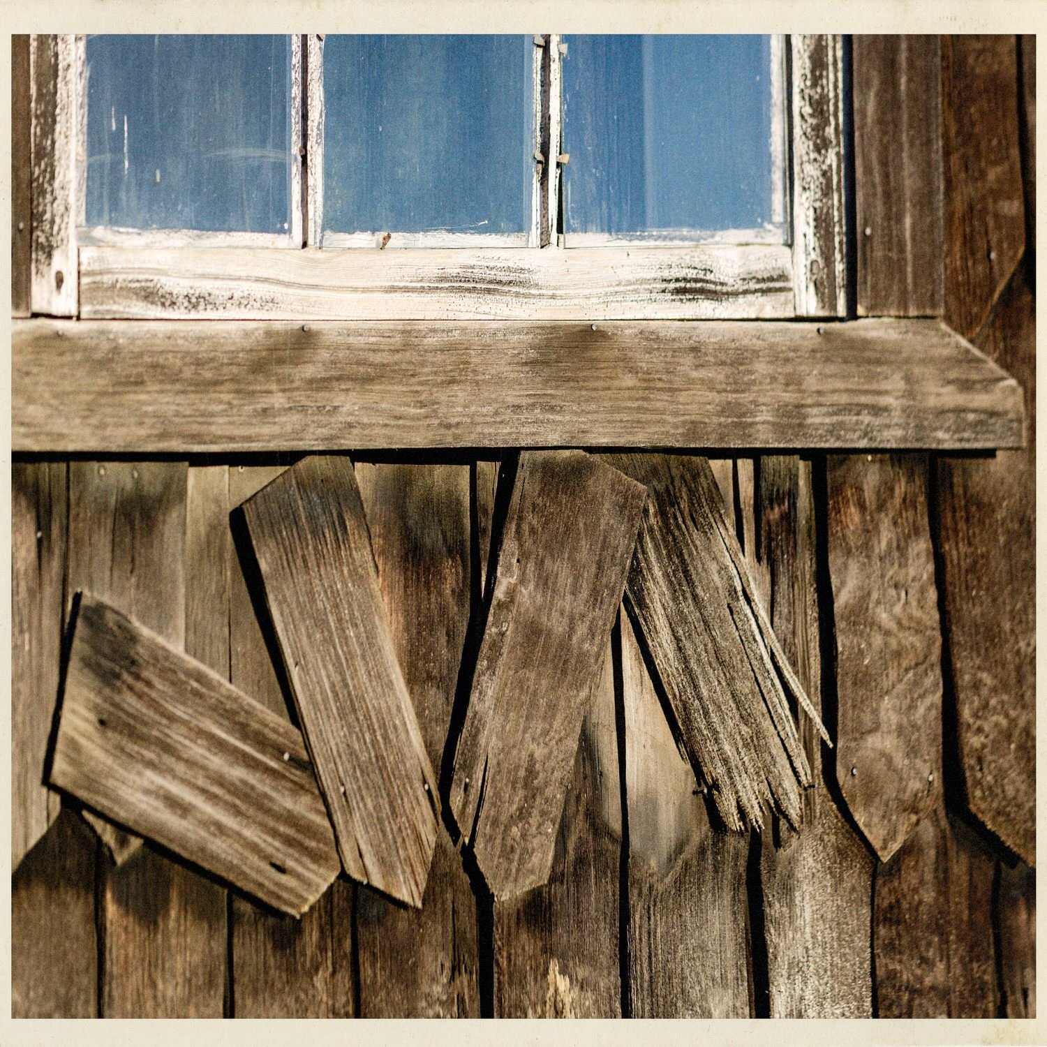 Tejuelas de madera sueltas bajo una ventana, en el muro de la iglesia de Chullec