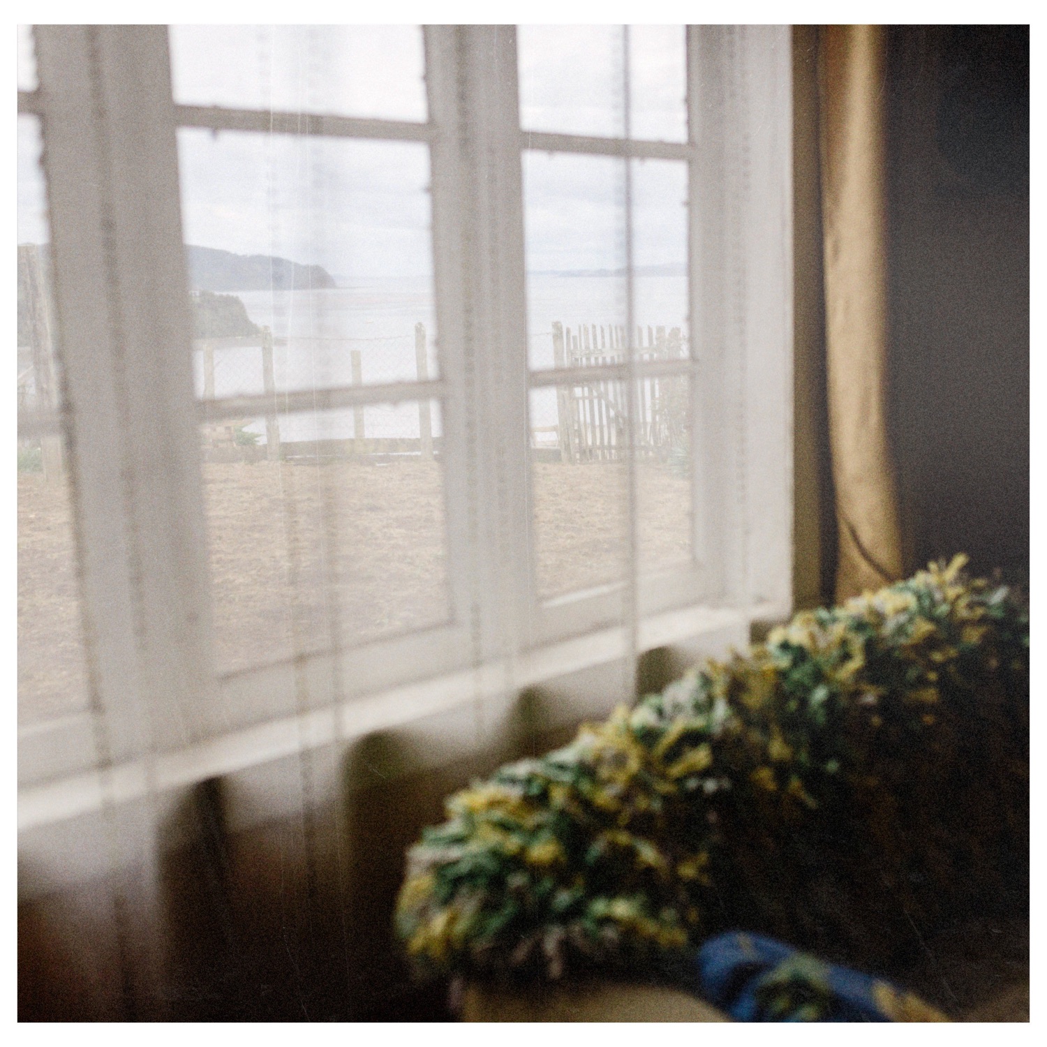 Ventana con cortinas y el mar al fondo, en una casa de Chullec