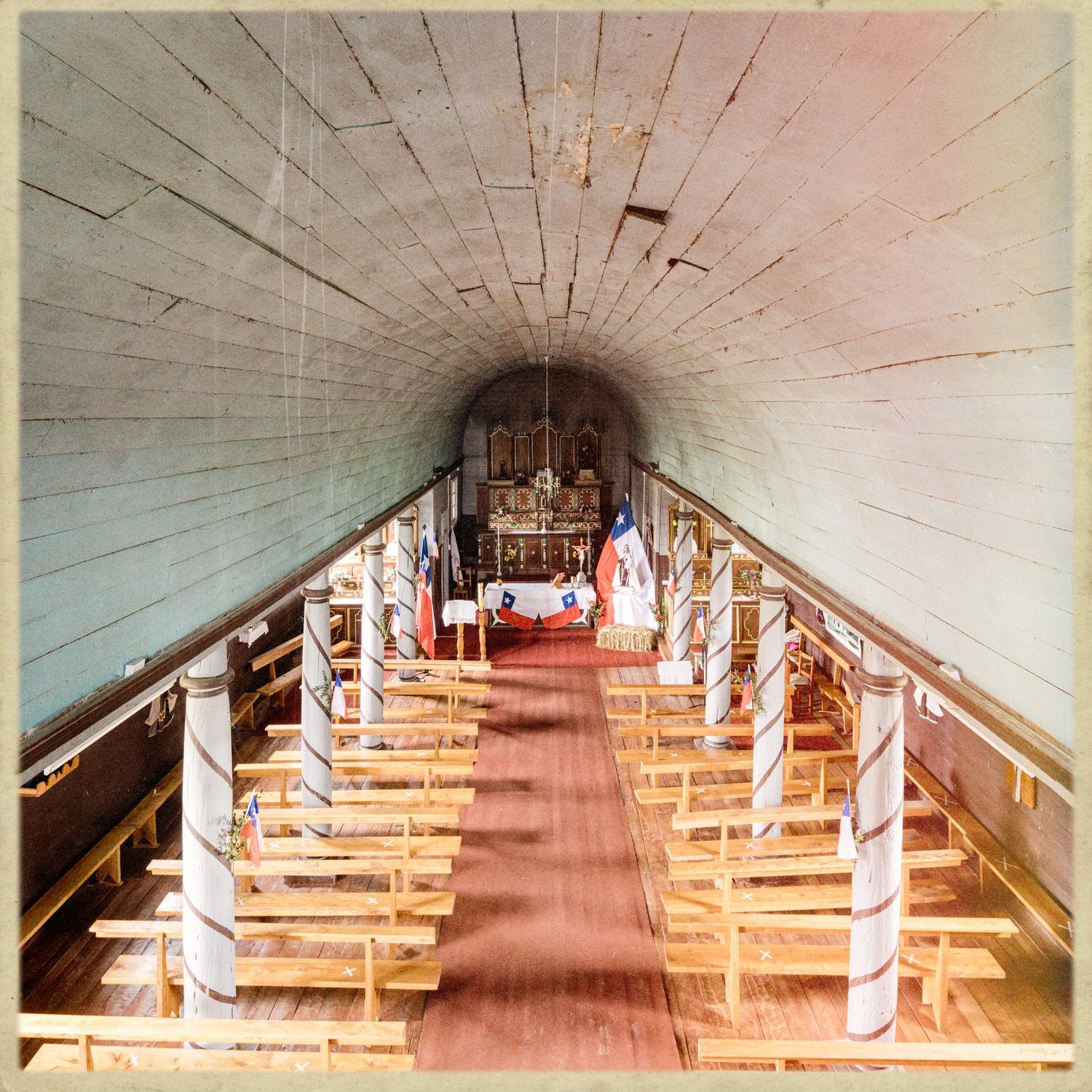 Nave de la iglesia de Compu con bóveda de madera, columnas y bancas