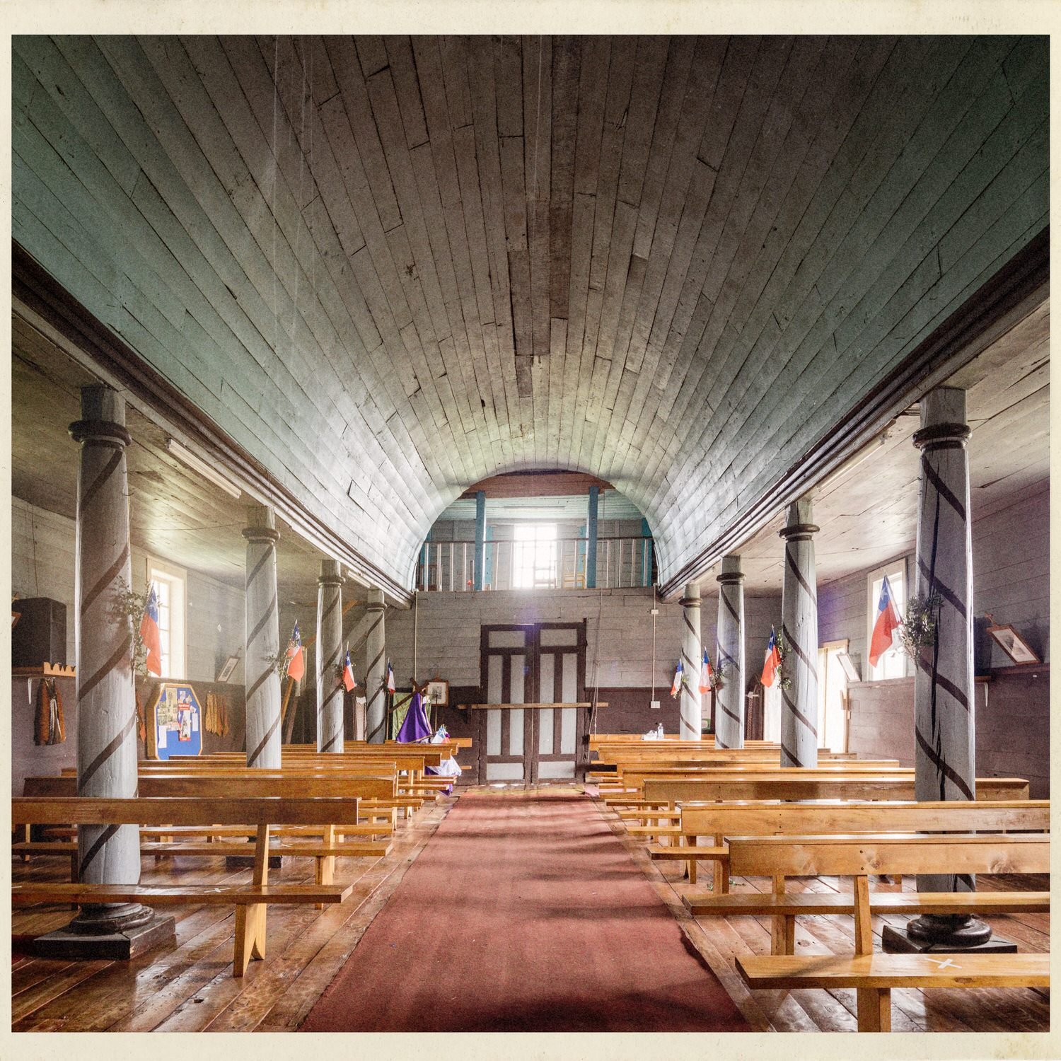 Interior de la iglesia de Compu hacia la entrada, con columnas y bancas