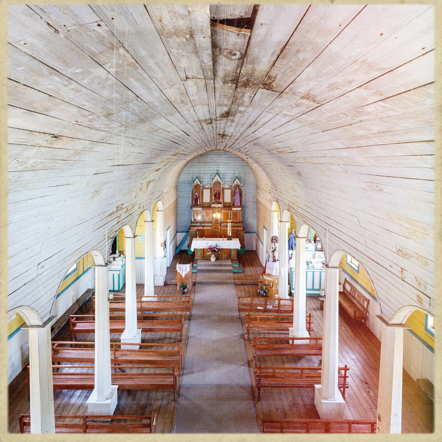Nave de la iglesia de Lincay con bóveda de madera, arcos y columnas blancas
