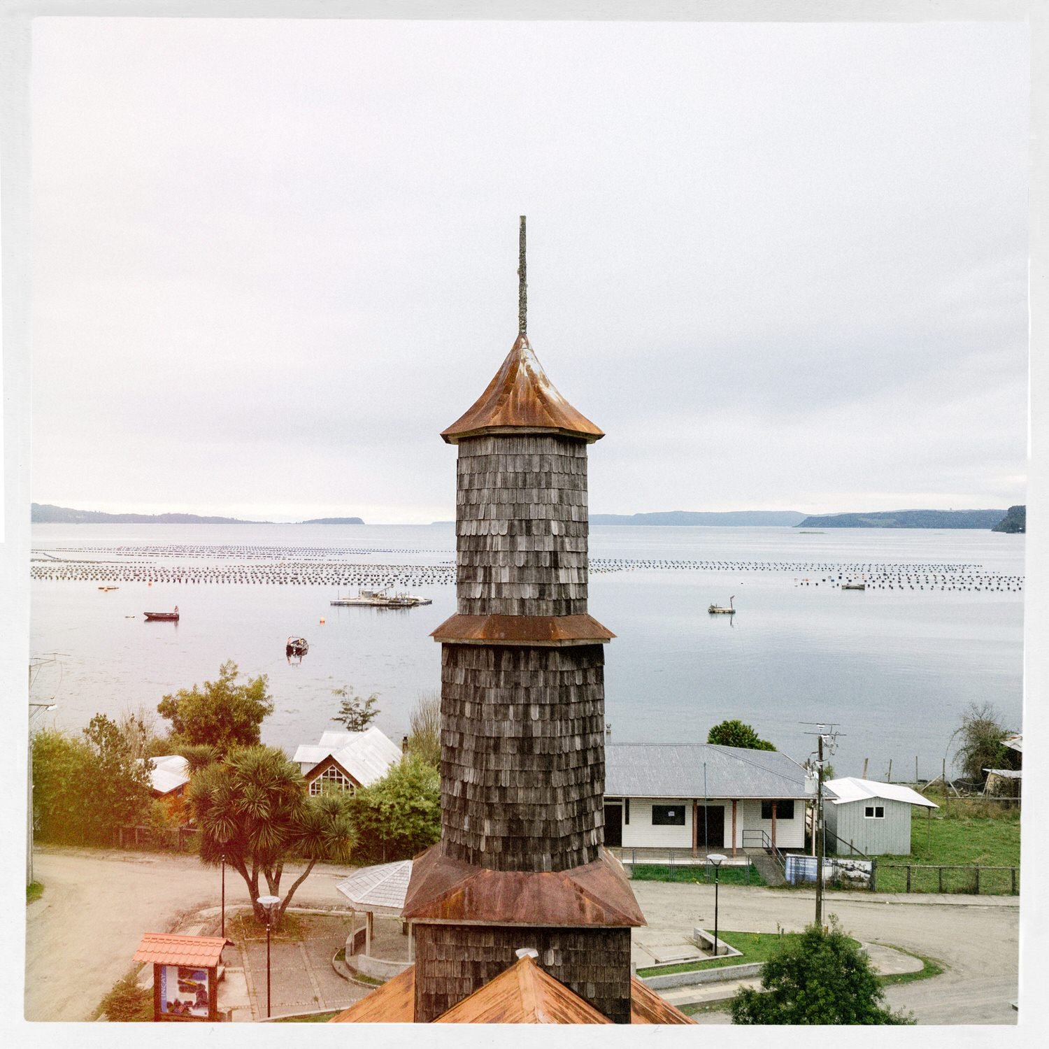 Torre de la iglesia de Lincay vista desde lo alto, con el mar y los cultivos al fondo