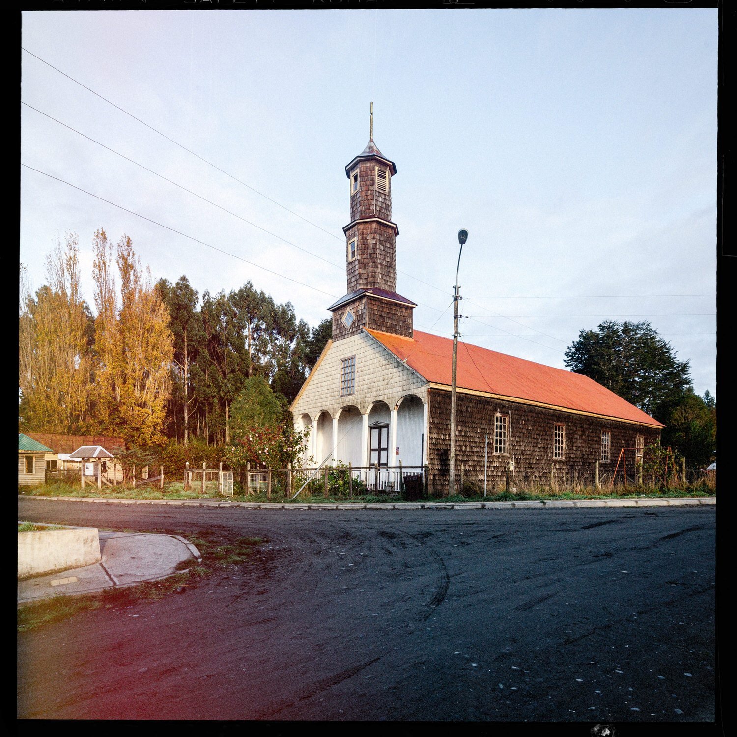 La iglesia de Lincay vista en diagonal, con techo rojo y torre alta