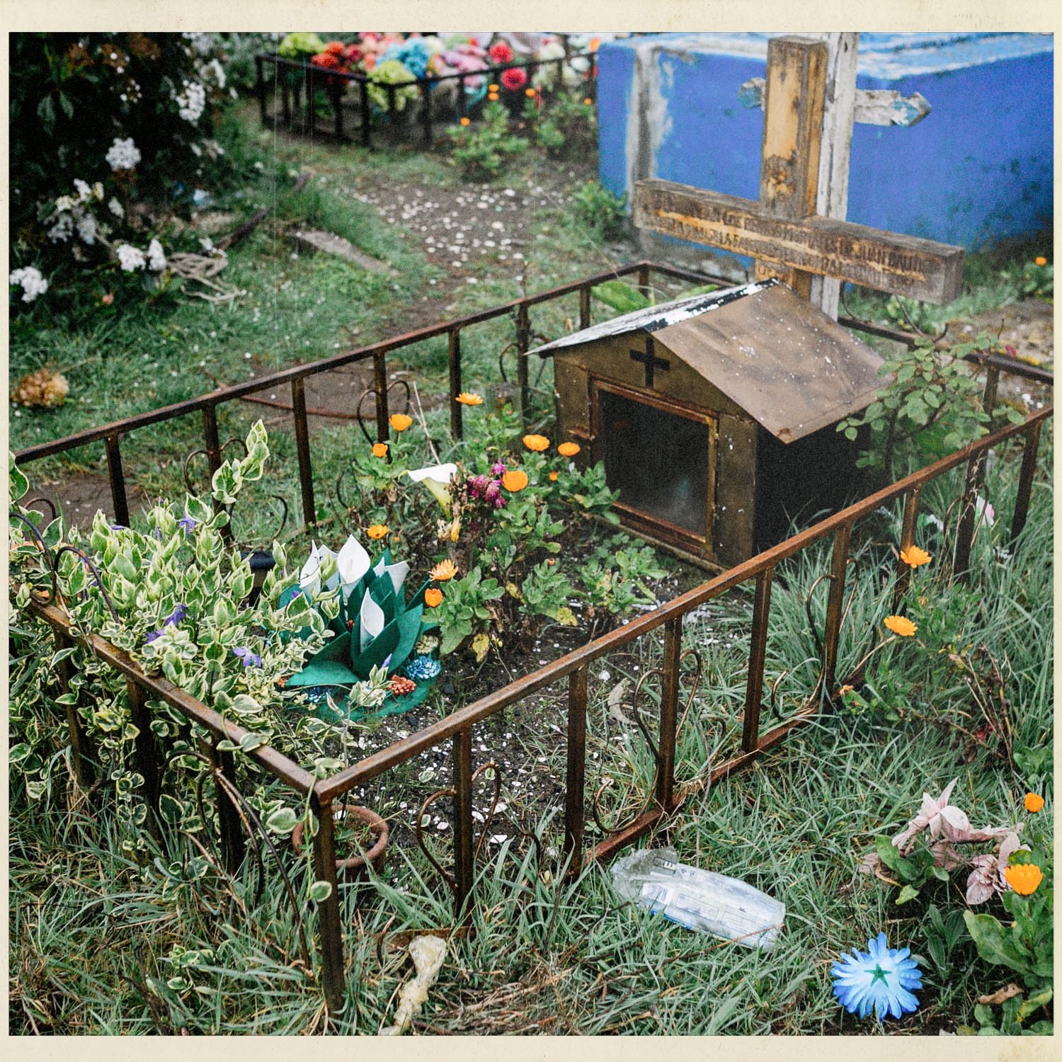 Tumba cercada con flores y una casita de madera, en el cementerio de Llingua