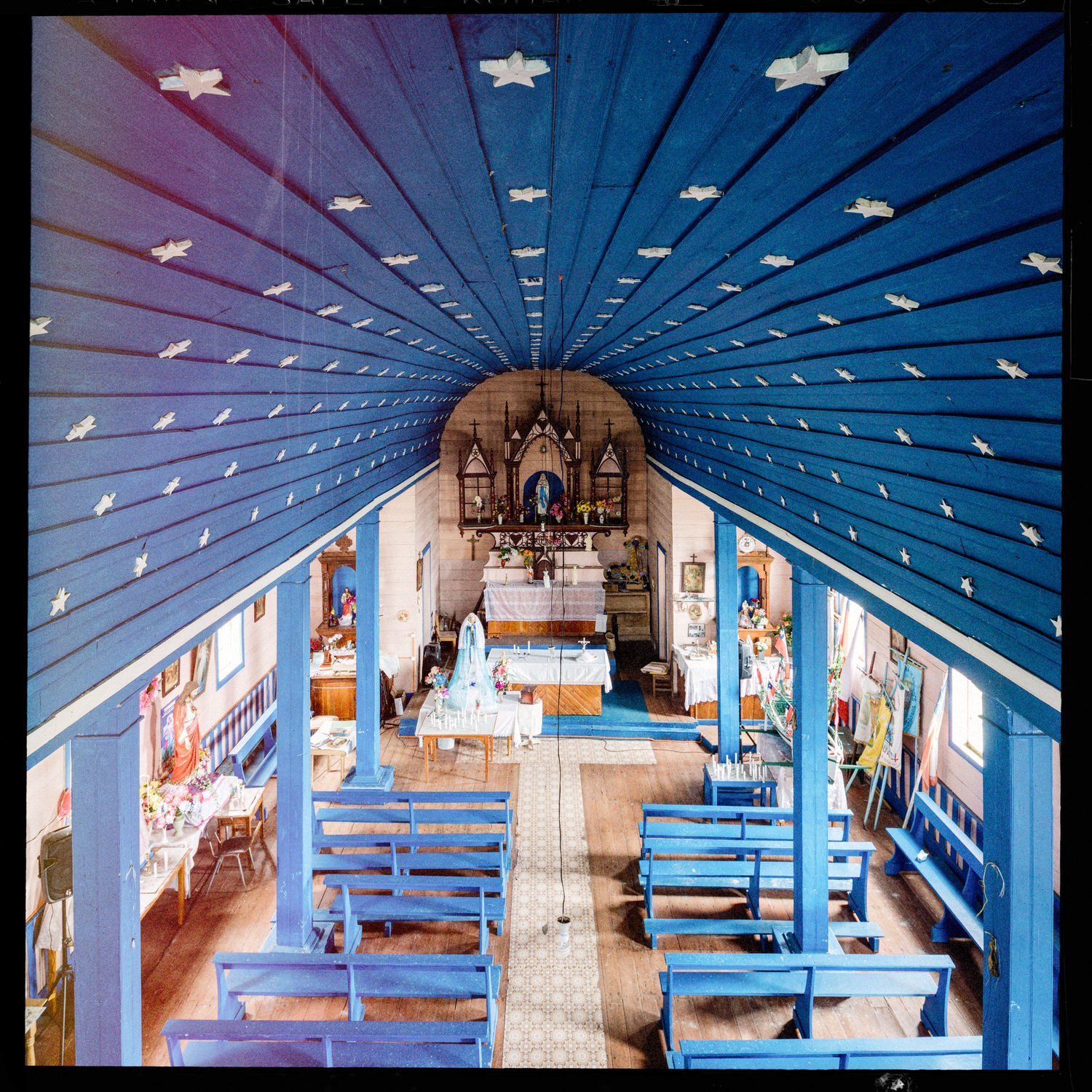 Nave de la iglesia de Llingua con bóveda azul estrellada y bancas azules