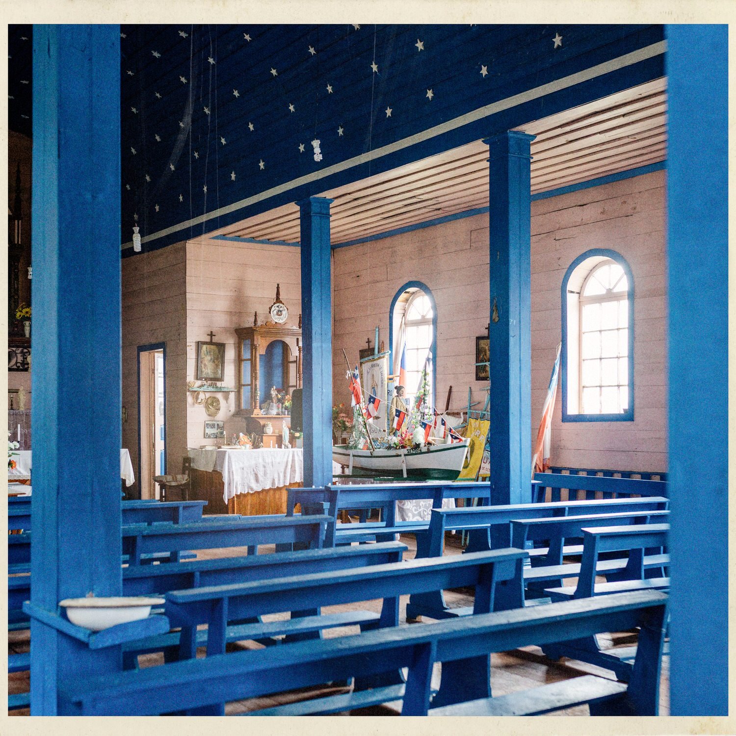 Columnas y bancas azules en el interior de la iglesia de Llingua