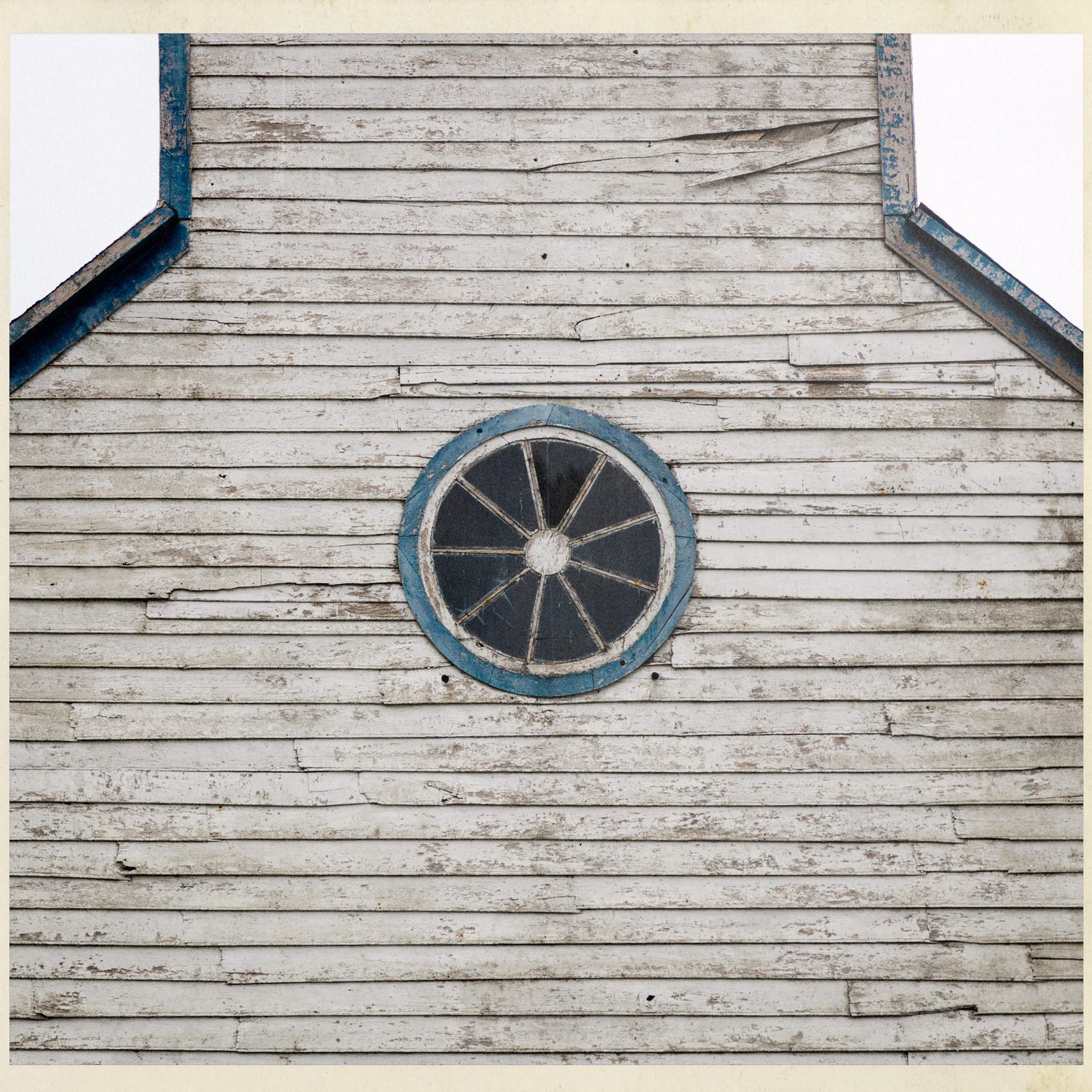 Frontis de tablas blancas con ventana circular, en la iglesia de Llingua