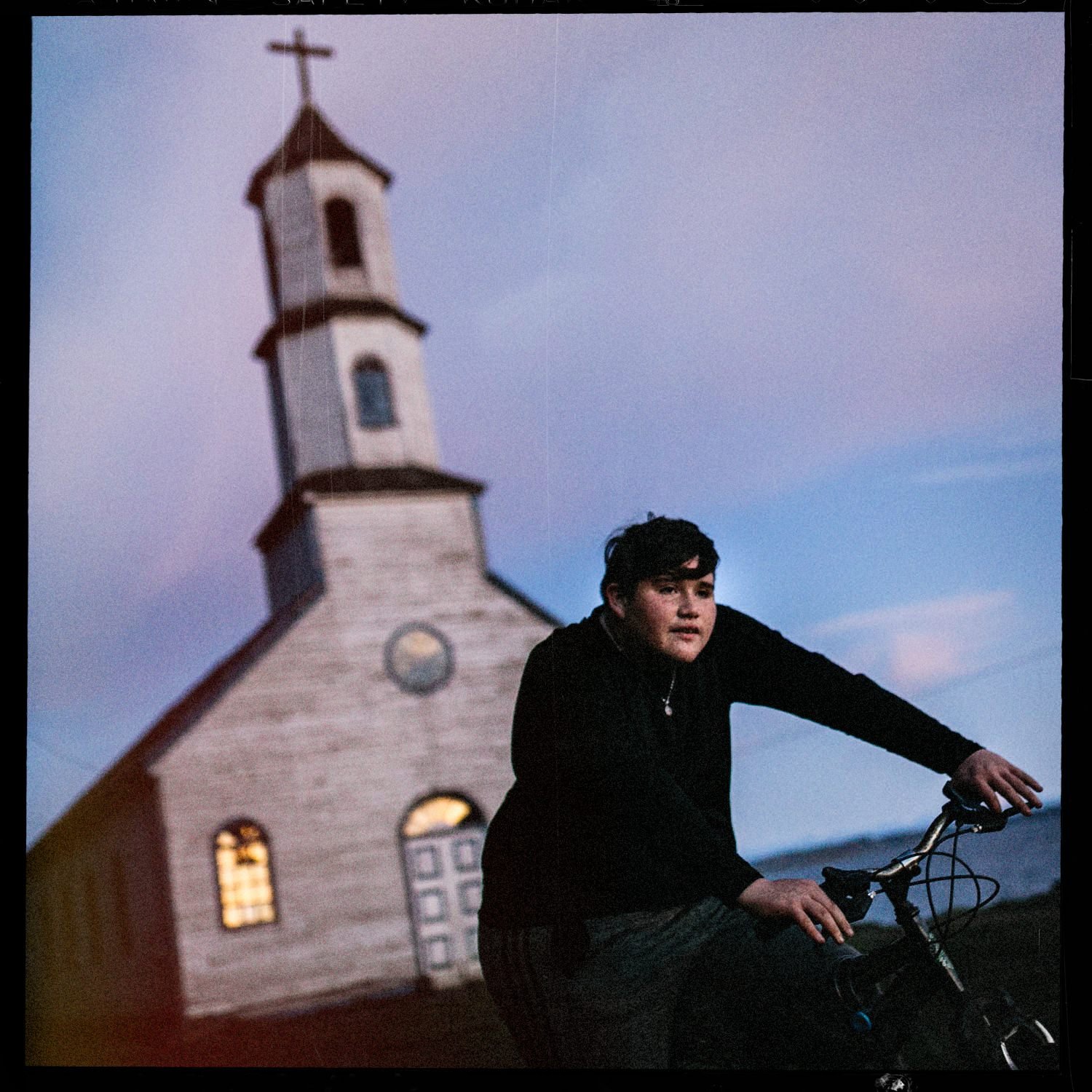 Juan José en bicicleta frente a la iglesia de Llingua, al atardecer