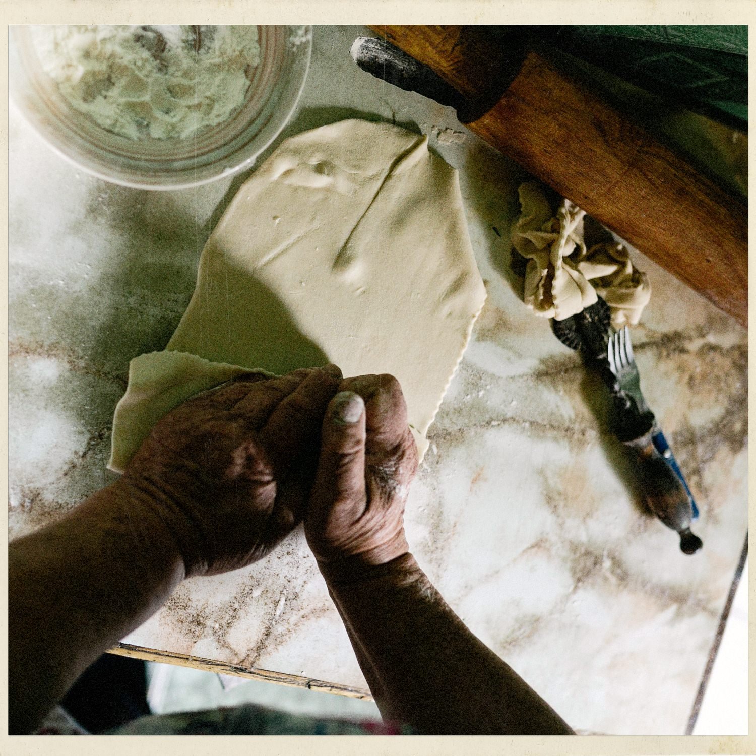 Manos estirando masa sobre una mesa