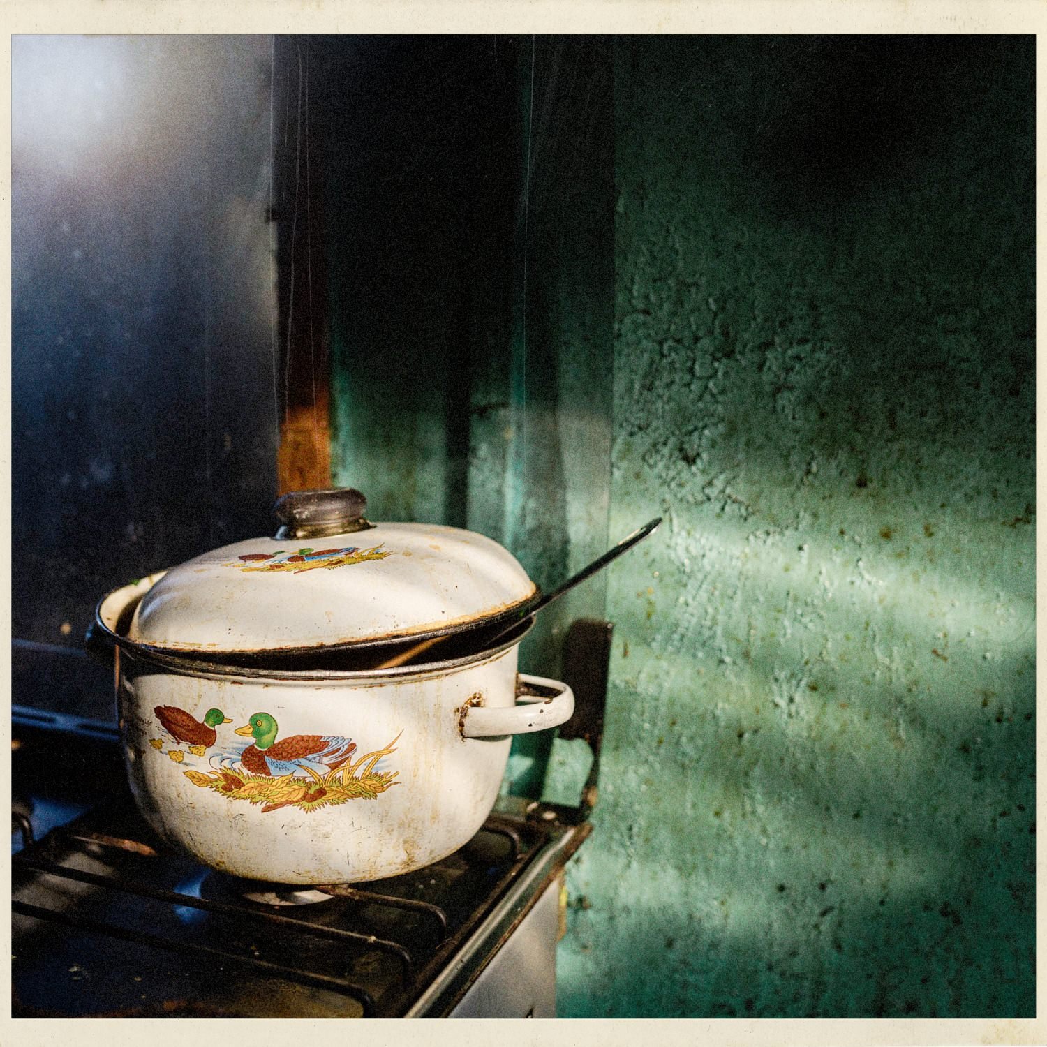 Olla enlozada sobre una cocina, con luz de ventana
