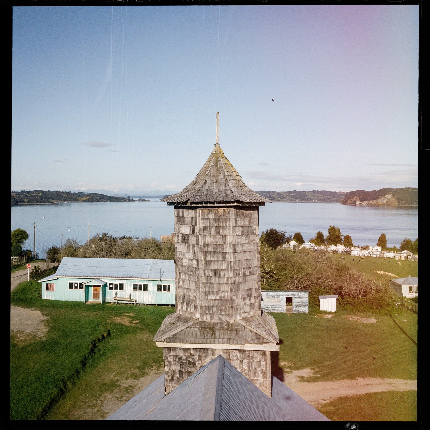 Torre de la iglesia de Puchilco vista desde lo alto, con el mar y el caserío