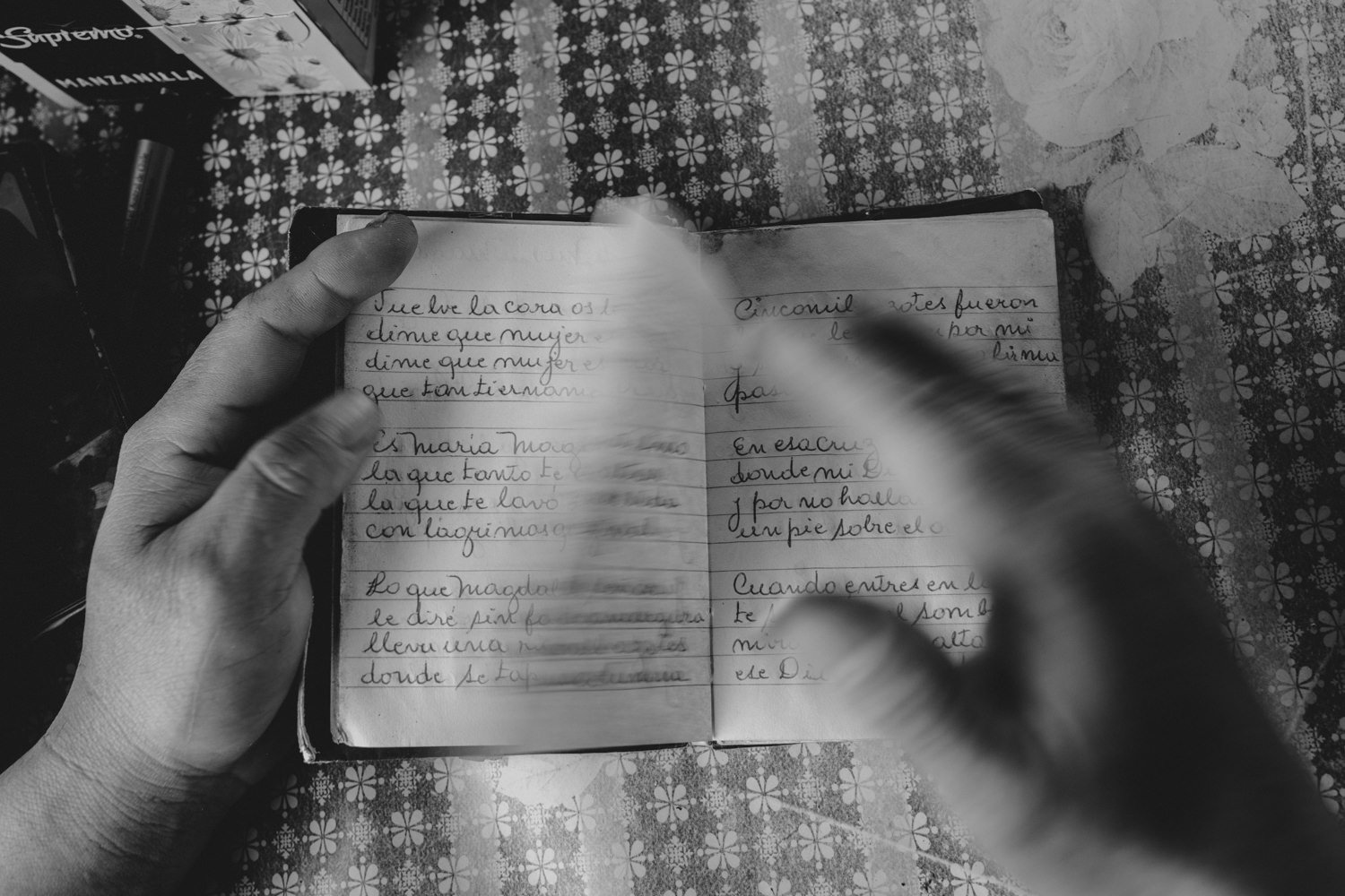 Manos sosteniendo un cuaderno escrito a mano, en blanco y negro
