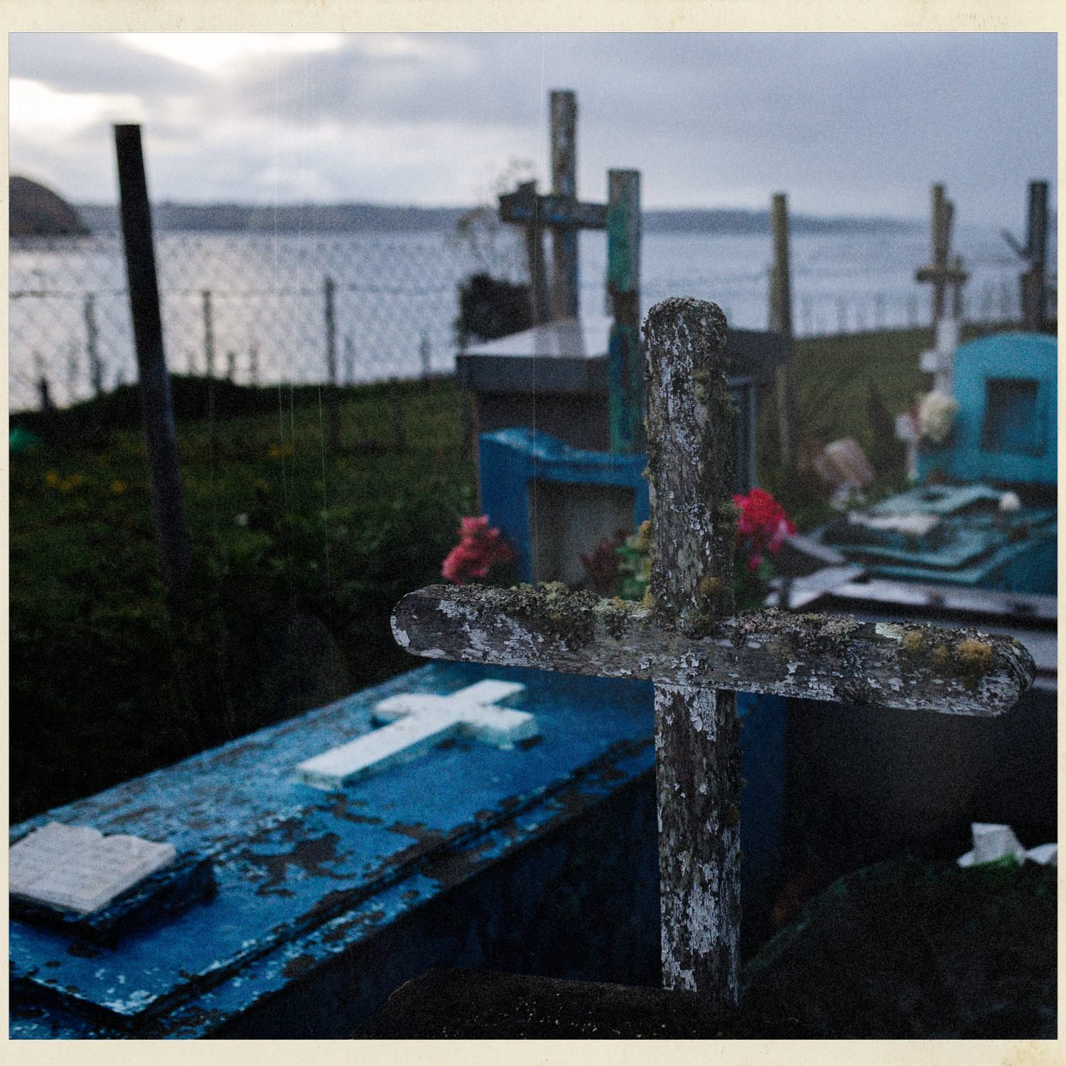 Cruz de madera y tumbas azules en el cementerio de Quehui