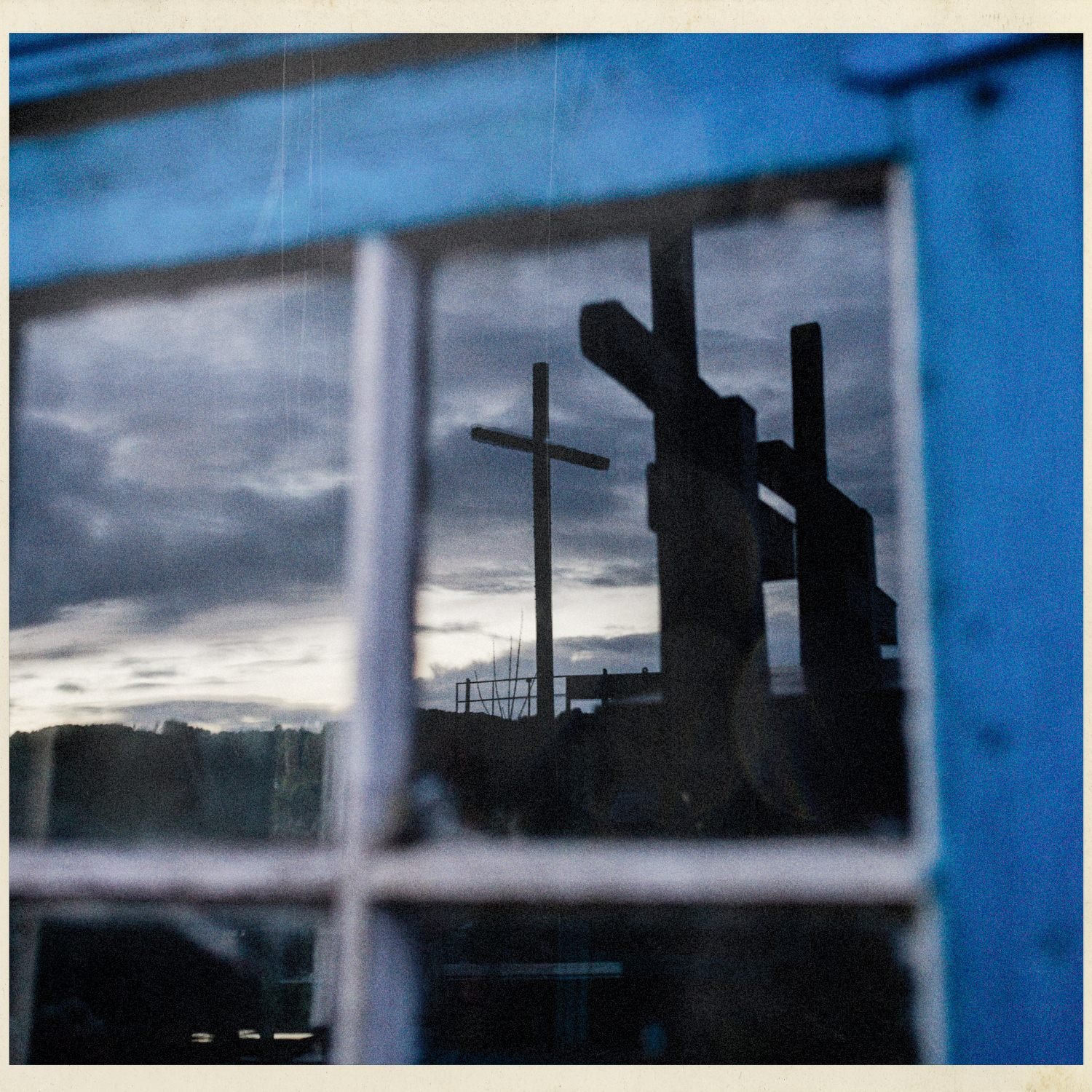 Cruces del cementerio vistas a través de una ventana azul