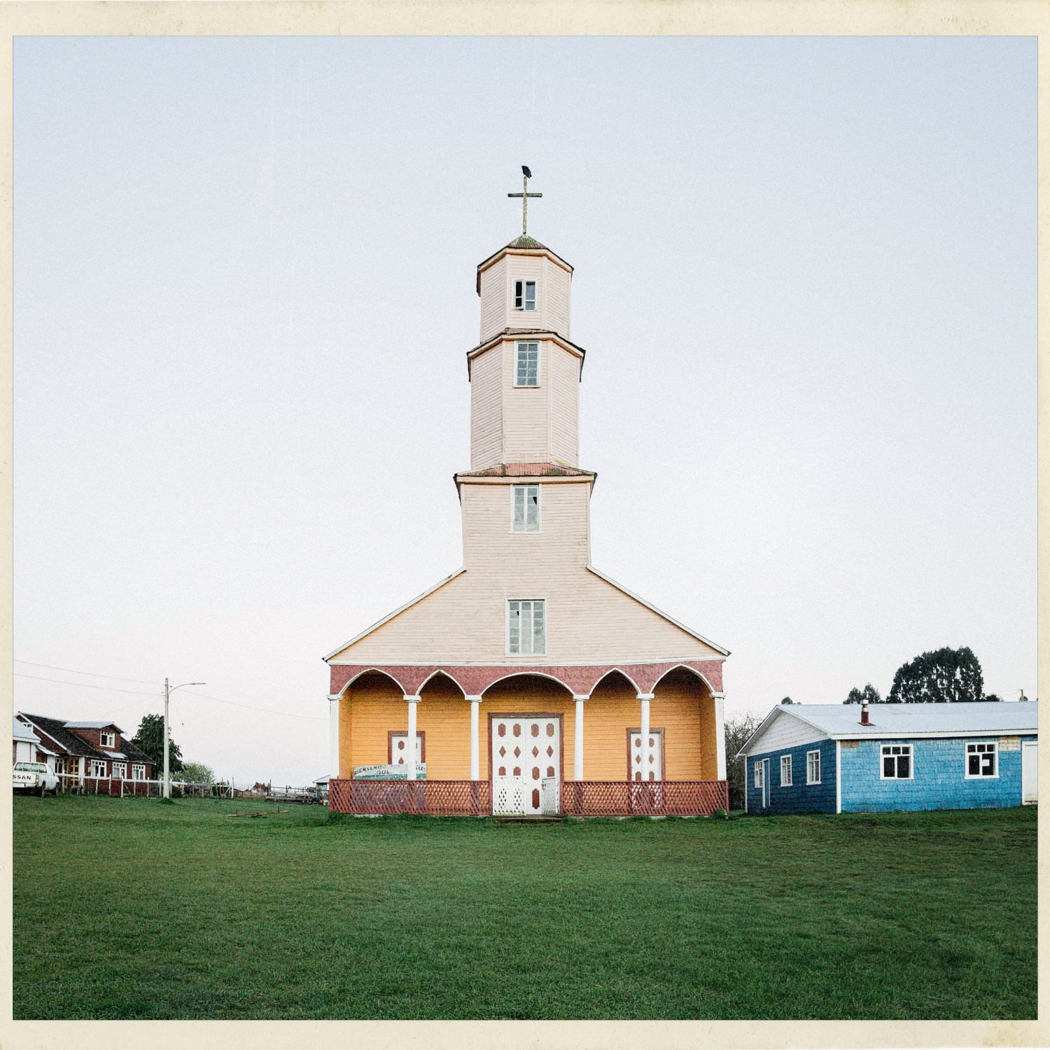 La iglesia de Quehui con su torre alta, en una explanada de pasto