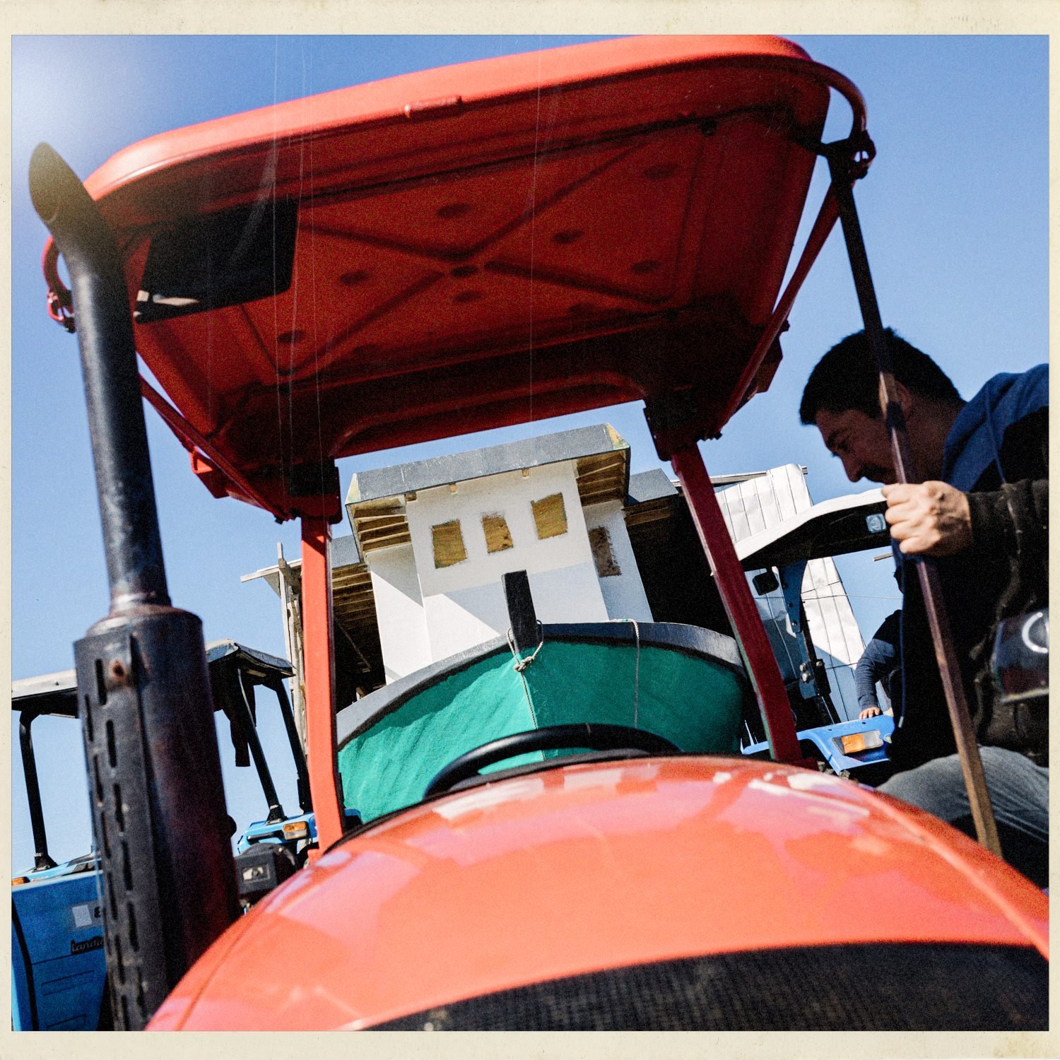 John Llanquin en un tractor rojo frente a una lancha en construcción