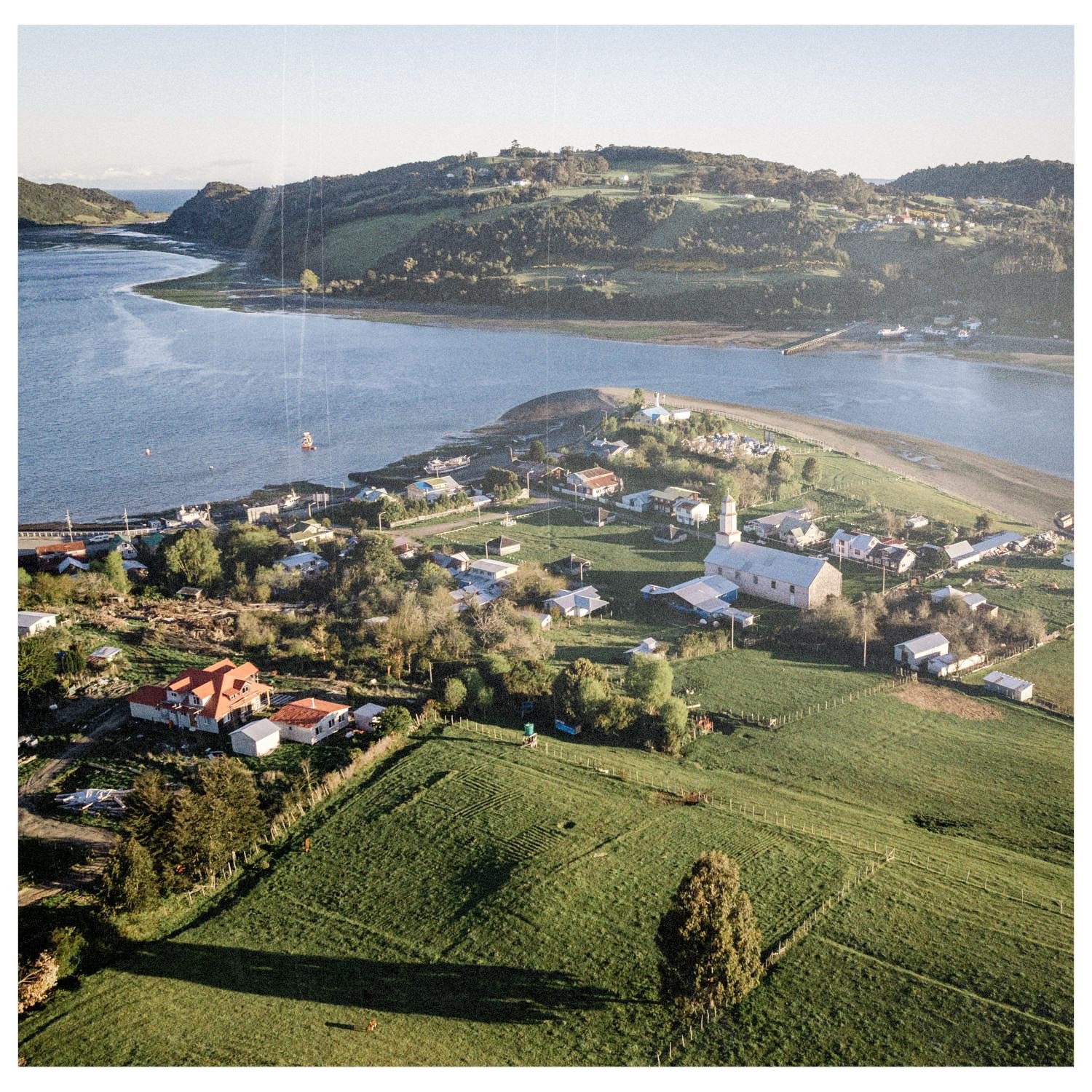 Vista aérea del caserío de Quehui con la iglesia, los campos y el estero