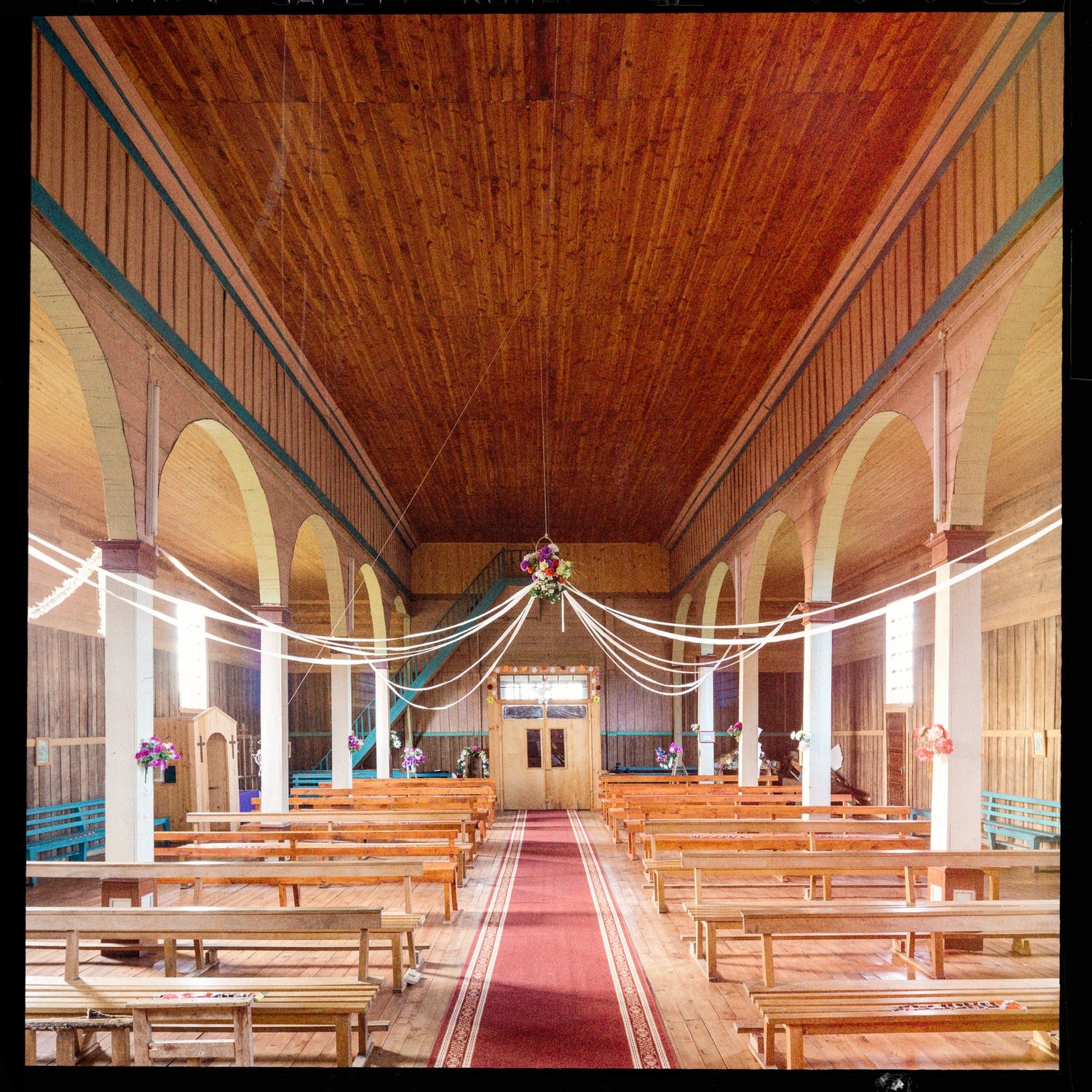 Interior de la iglesia de San Javier hacia la entrada, con guirnaldas y alfombra roja
