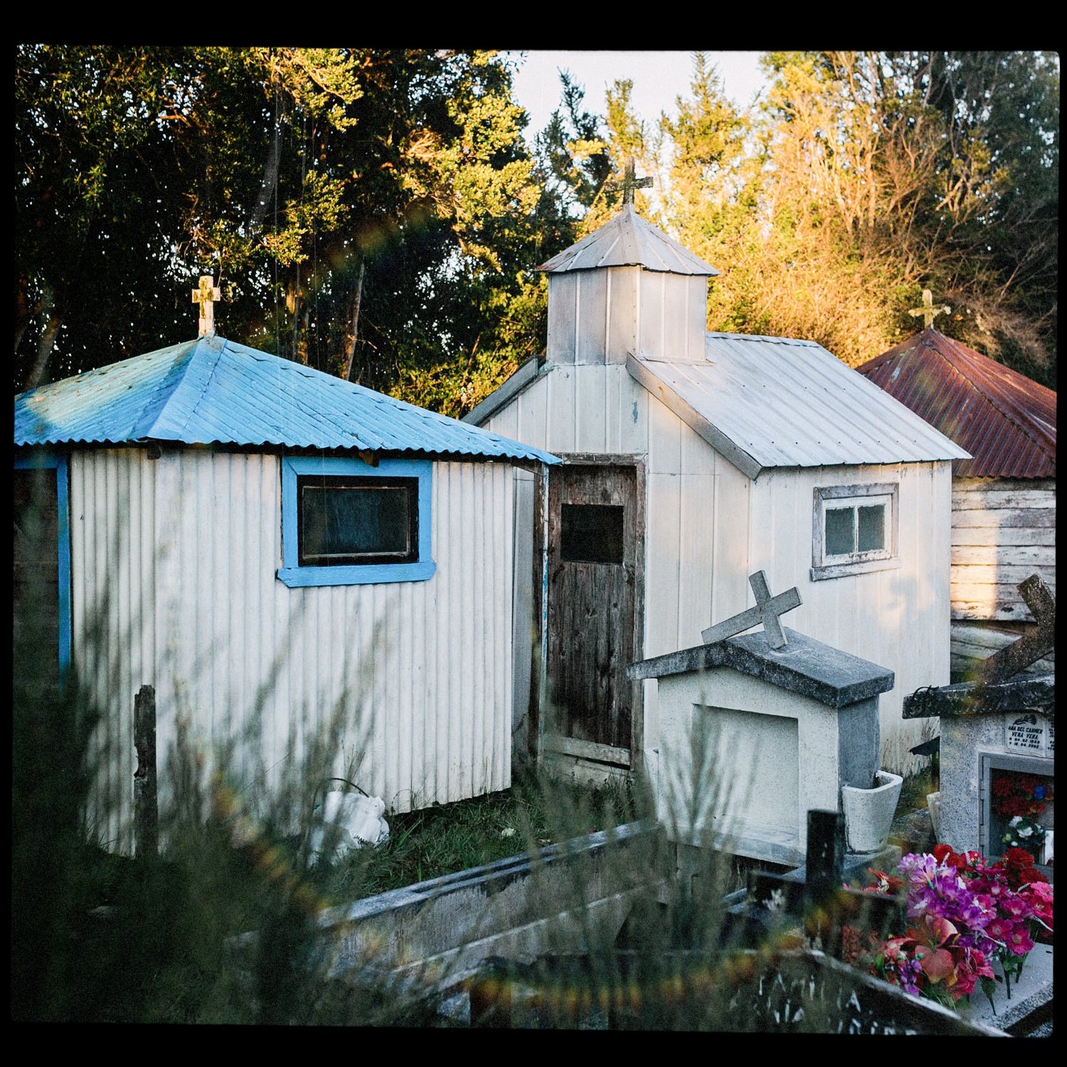 Casitas funerarias blancas y azules en el cementerio de Teupa