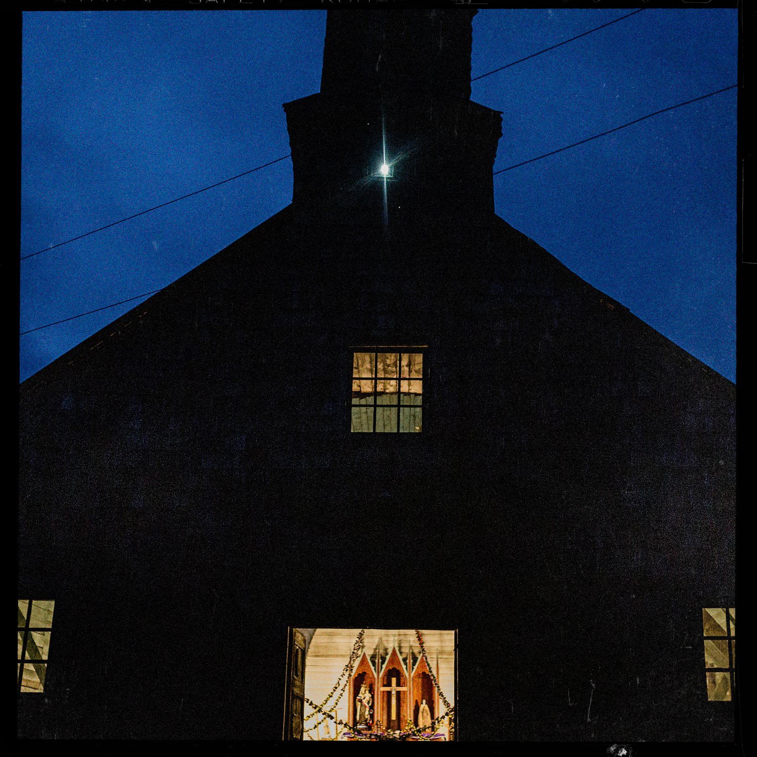 Frontis de la iglesia de Teupa al anochecer, con las ventanas iluminadas