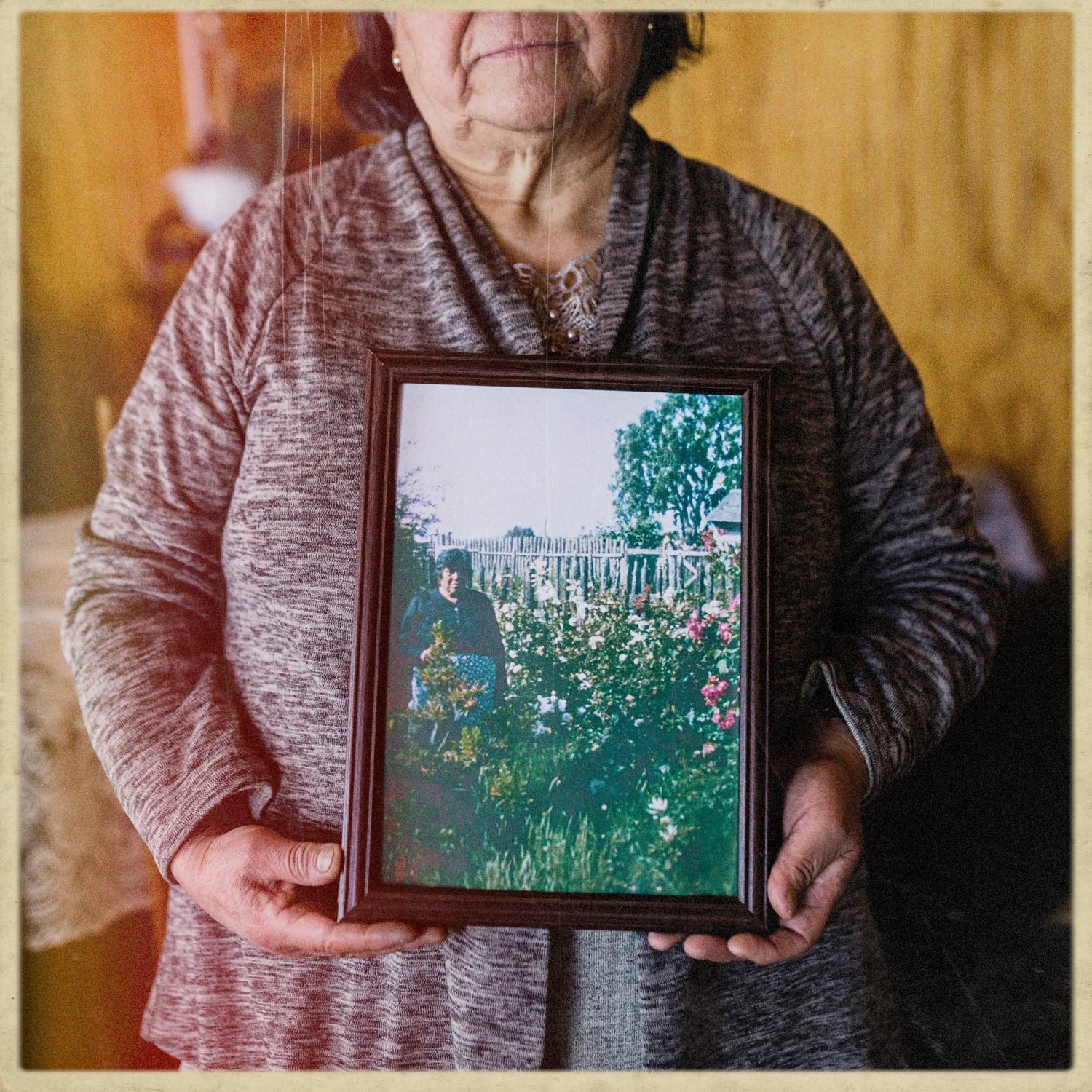 Doña Tita sostiene una fotografía enmarcada de un jardín