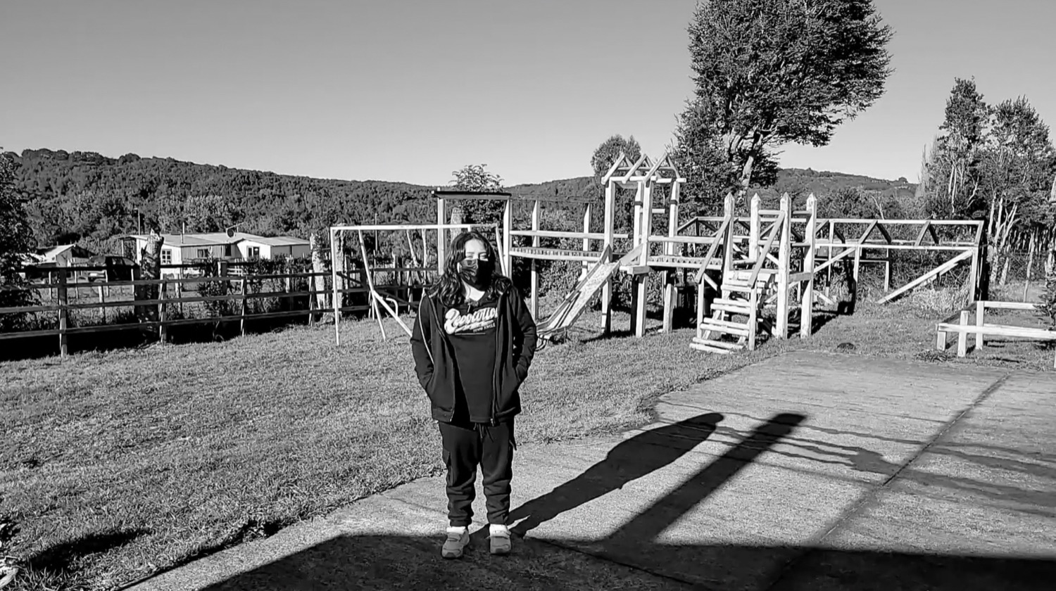 Rafaela de pie frente a juegos infantiles de madera, en blanco y negro