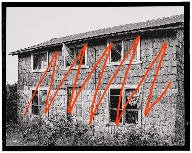 Edificio antiguo de madera con ventanas rotas y vegetación en primer plano en un área rural en blanco y negro con líneas rojas en zigzag sobre la imagen.