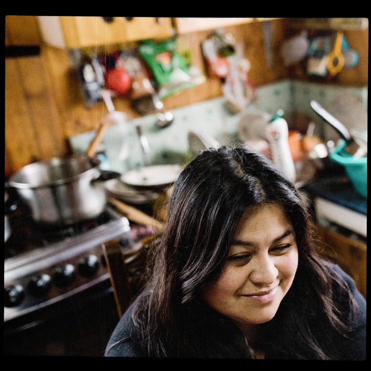 Mujer con cabello oscuro en una cocina desordenada