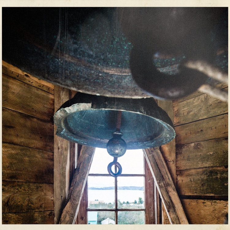 Campana en el interior de la torre de la iglesia, con el mar por la ventana