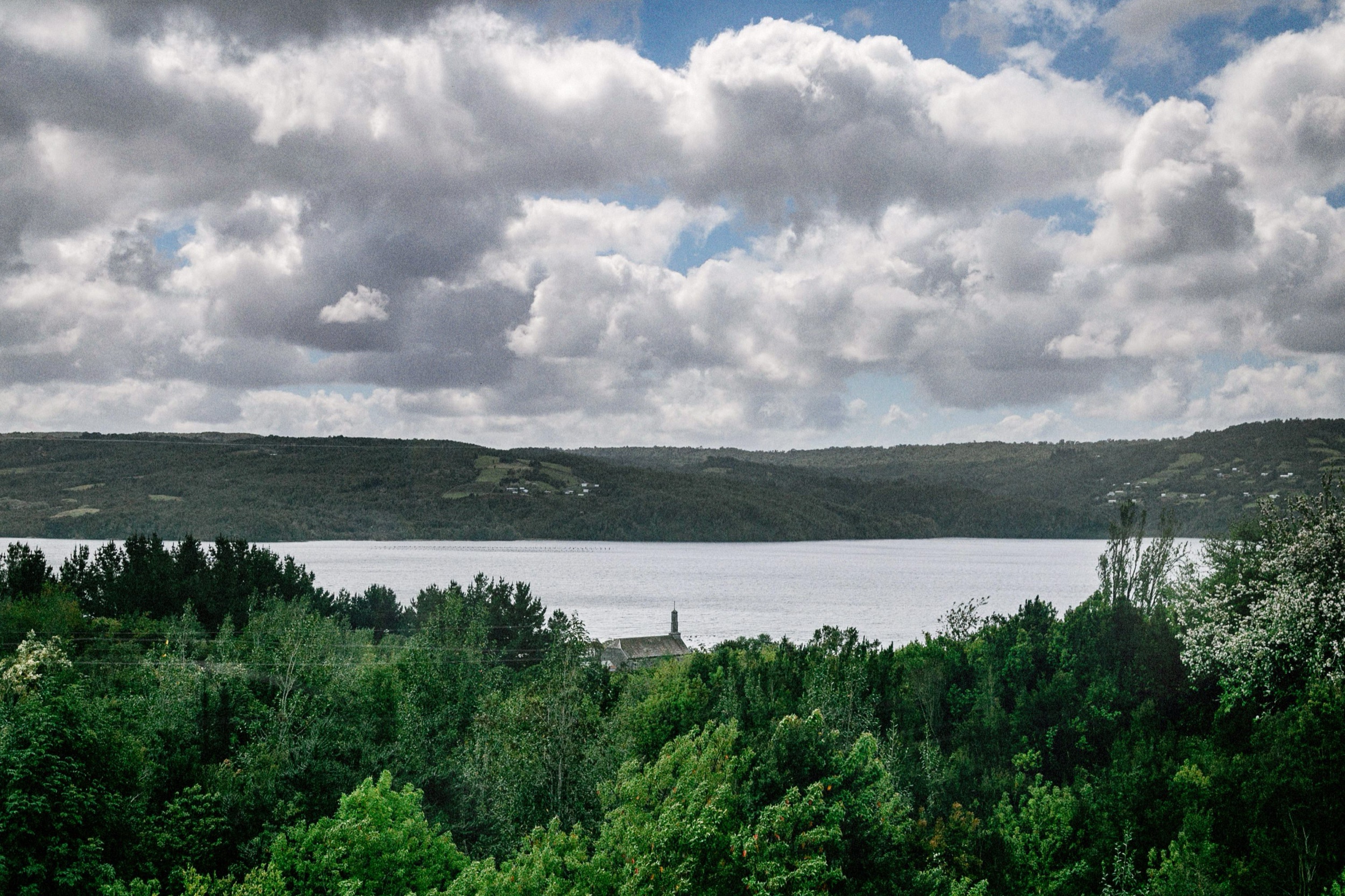 Paisaje de Compu con bosque, el mar y un cielo con nubes