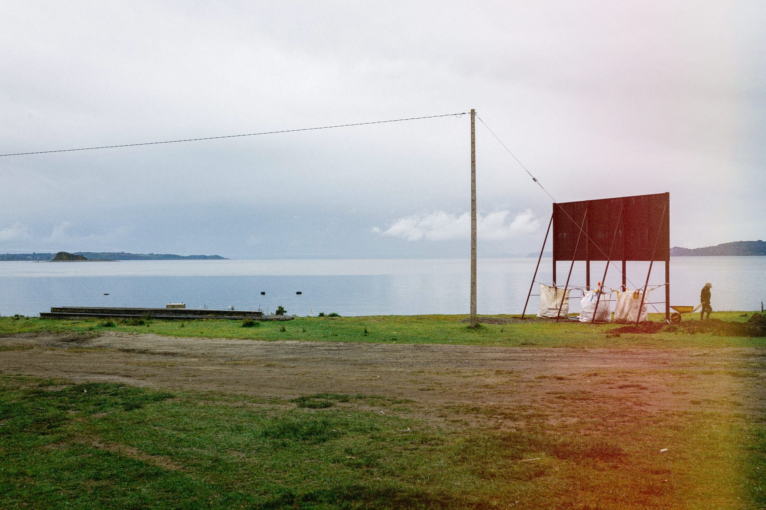 Un letrero y un poste en un campo junto al mar, en Llingua