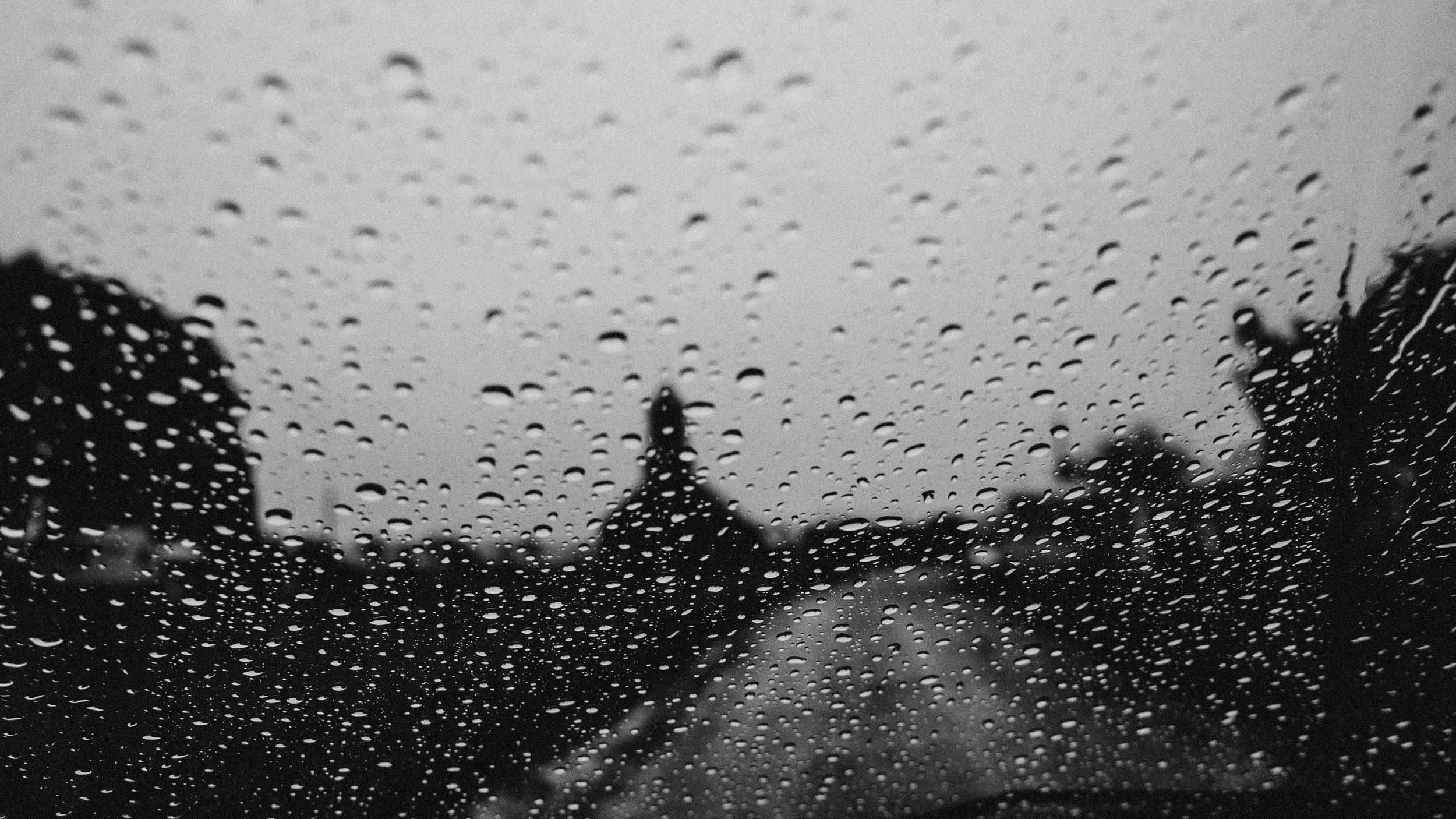 Camino rural visto a través de un parabrisas mojado por la lluvia, en blanco y negro