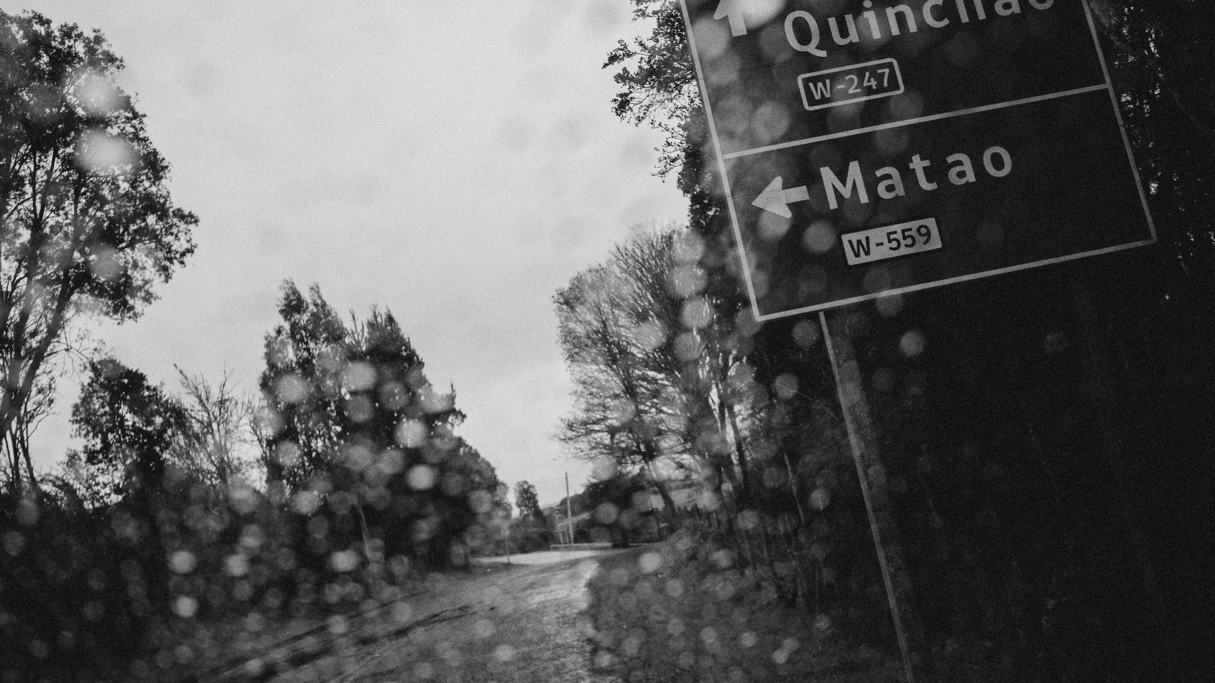 Letrero de camino que indica la dirección a Matao, bajo la lluvia, en blanco y negro
