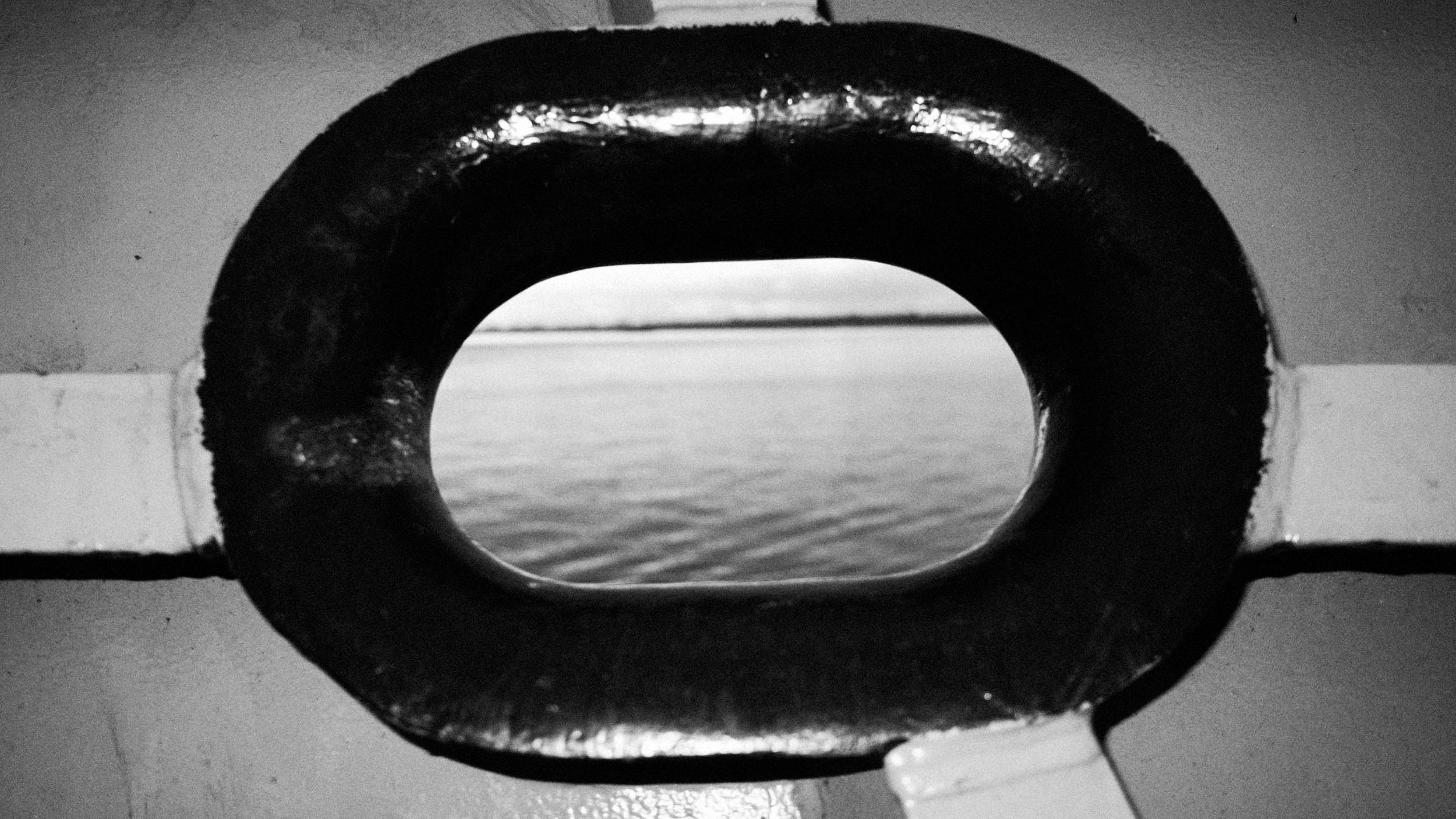 El mar visto a través de una ventanilla ovalada de una embarcación, en blanco y negro