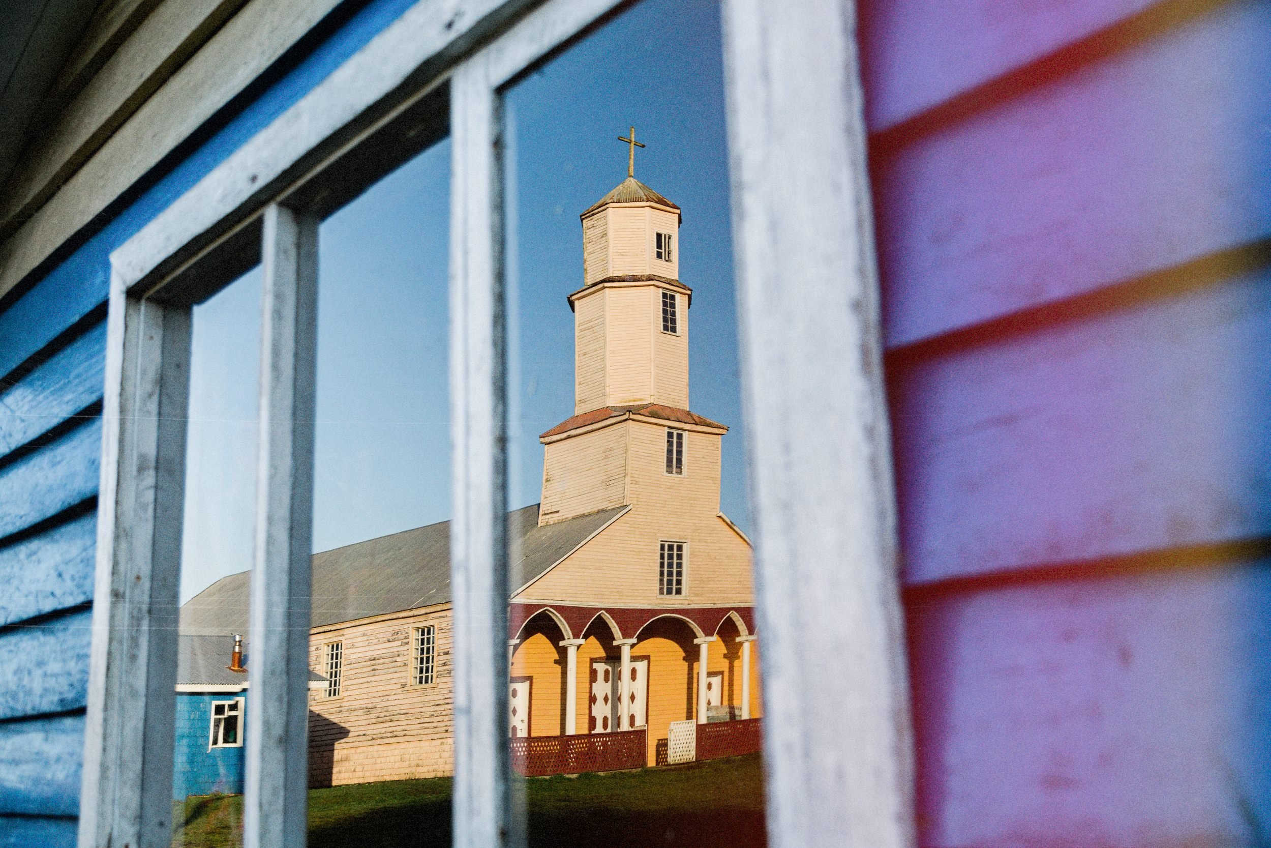 La iglesia de Quehui vista a través de una ventana de una casa