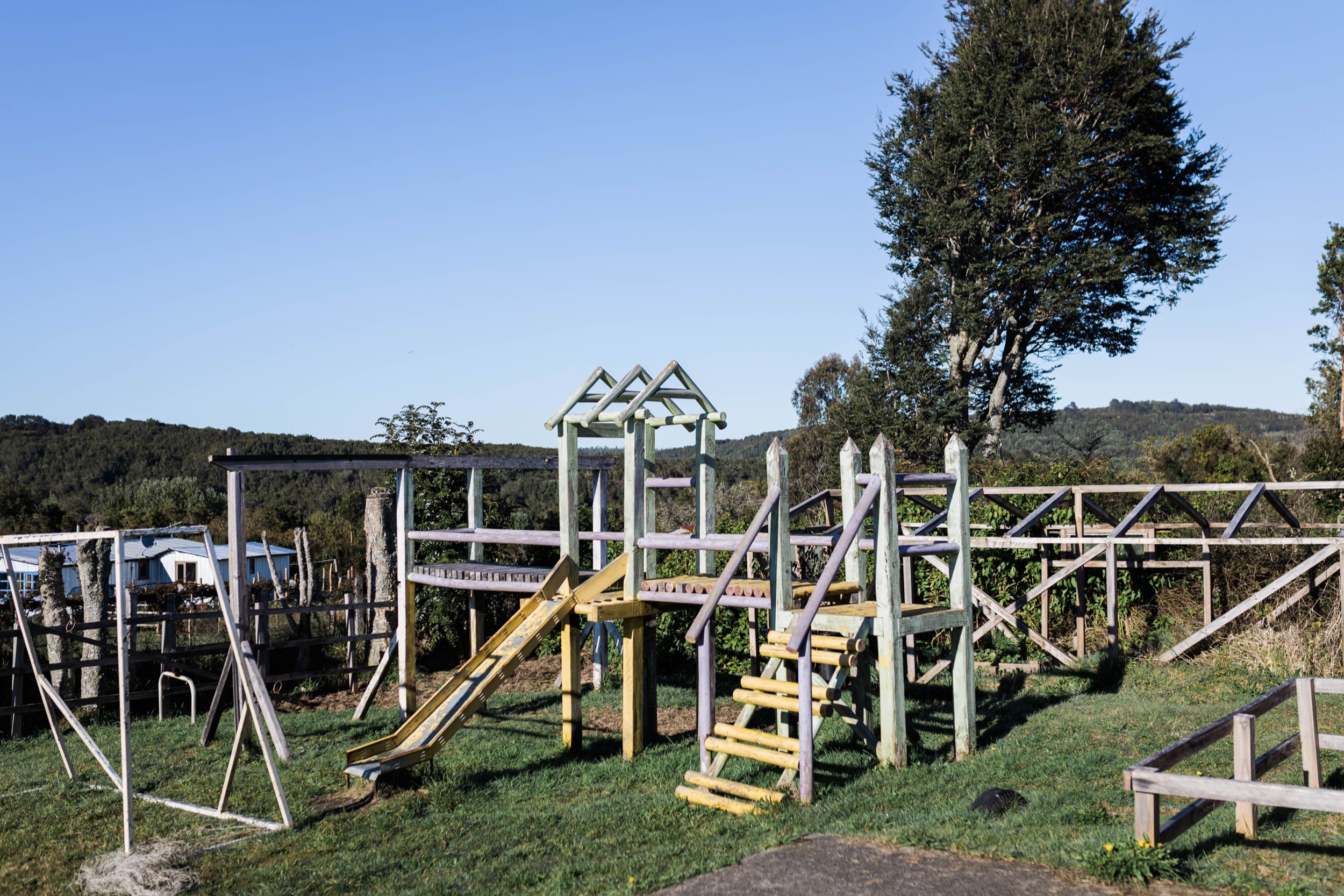 Juegos infantiles de madera en un campo, bajo un cielo azul